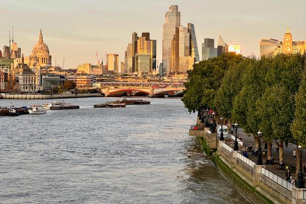 A view up the Thames River towards London City at sunset with a yellow glow on the buildings 