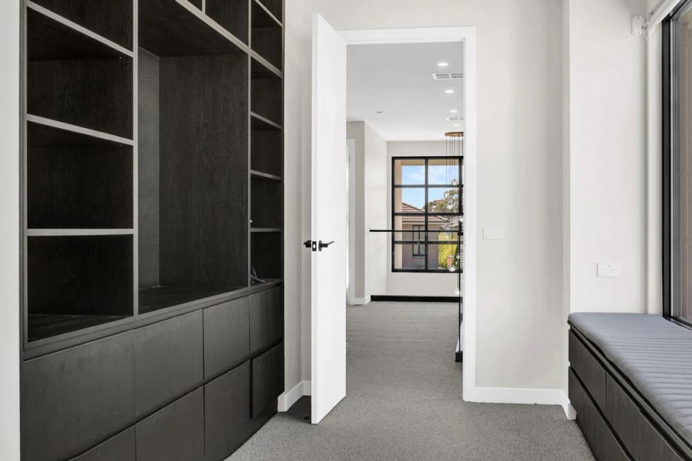 Walk-in robe with dark timber joinery opening to the hallway, Tiffany Walk Residence, Sanctuary Lakes
