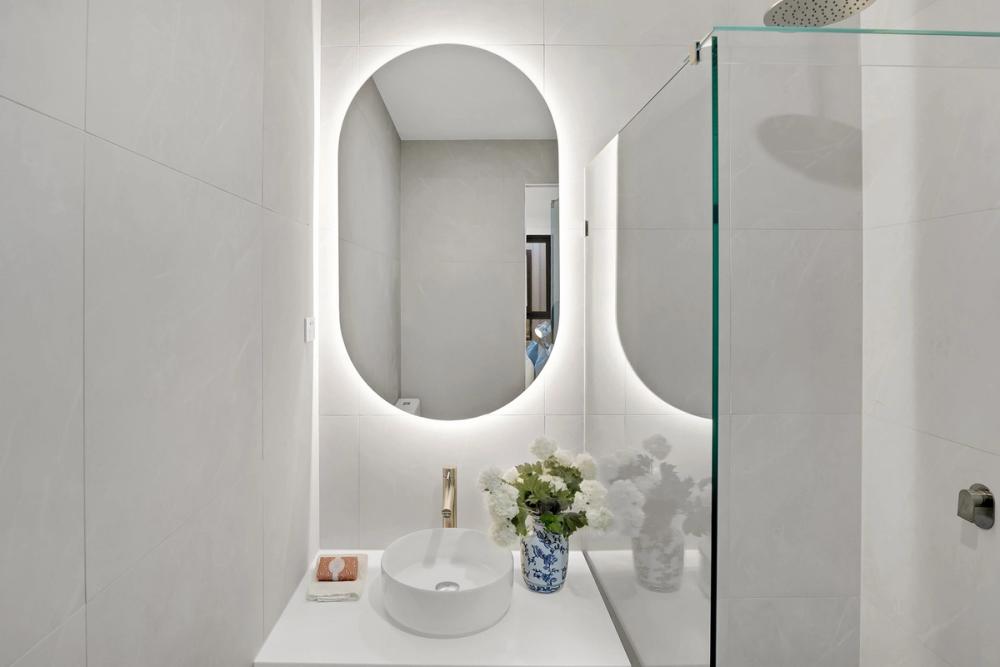 Ensuite with a backlit oval mirror, vessel basin on a floating vanity and glass shower, Tarneit Cathedral Residence, Melbourne