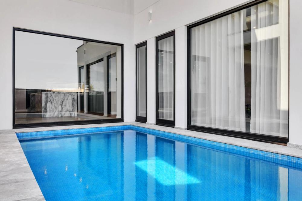 Lap pool alongside the home's full-height black-framed windows, Tiffany Walk Residence, Melbourne