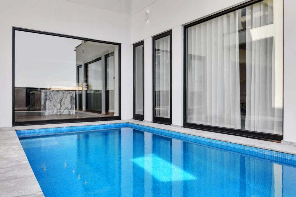 Lap pool alongside the home's full-height black-framed windows, Tiffany Walk Residence, Melbourne
