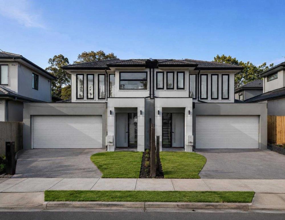 Two symmetrical rendered townhouses with double garages and dark-framed windows, Bentleigh East Development, Melbourne