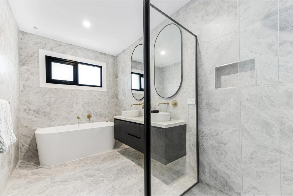 Bathroom with freestanding tub, glass shower and a black floating vanity in marble-look tiling, Bentleigh East Development, Melbourne