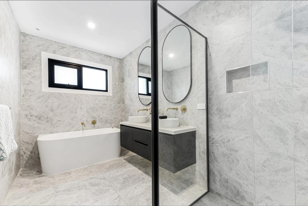 Bathroom with freestanding tub, glass shower and a black floating vanity in marble-look tiling, Bentleigh East Development, Melbourne