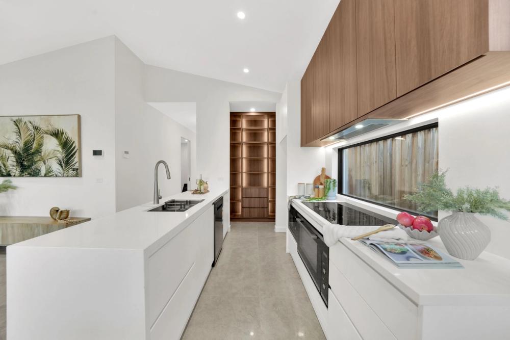 Kitchen with white island bench, timber cabinetry and a window splashback, Tarneit Cathedral Residence, Melbourne