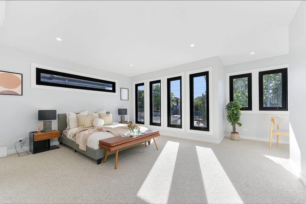 Master bedroom wrapped in black-framed windows with a bench seat, Bentleigh East Development, Melbourne