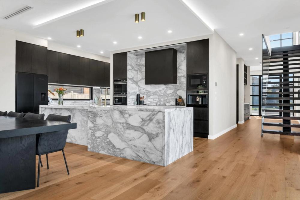 Kitchen and dining with a marble island and the staircase beyond, Tiffany Walk Residence, Melbourne