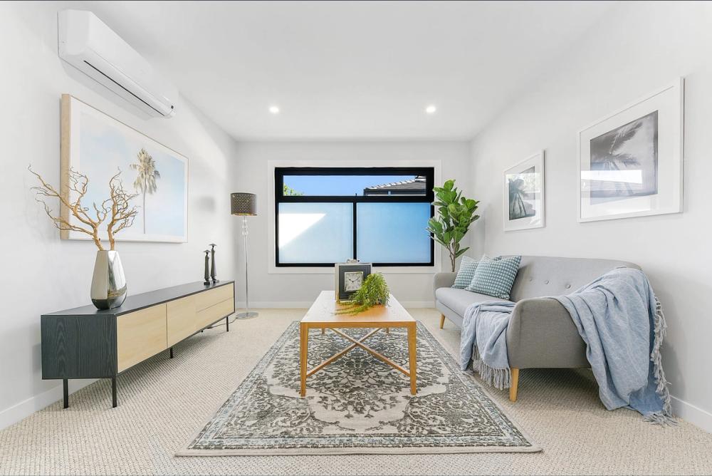 Lounge with grey sofa, timber sideboard and a patterned rug, Bentleigh East Development, Melbourne