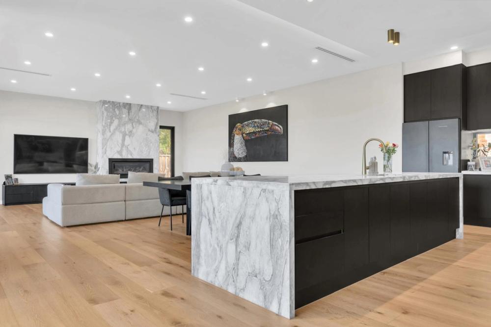 Open-plan living and kitchen with a marble island and marble fireplace wall, Tiffany Walk Residence, Melbourne