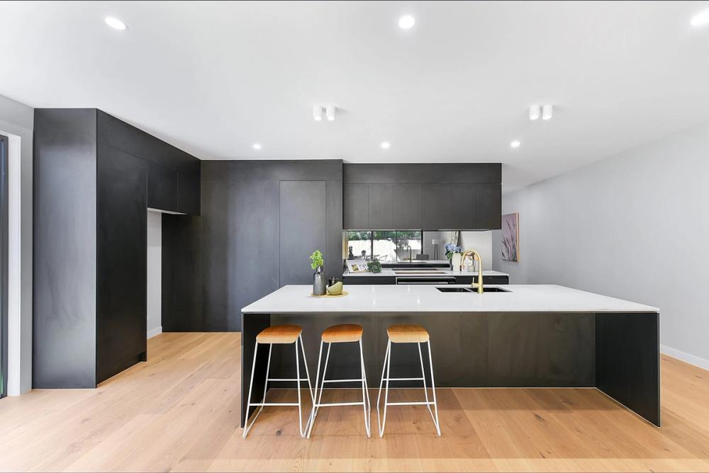 Kitchen with black cabinetry and a white waterfall island with bar stools, Bentleigh East Development, Melbourne