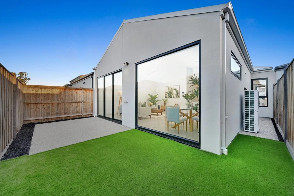 Landscaped rear yard at dusk with large living-room windows, Tarneit Cathedral Residence, Melbourne