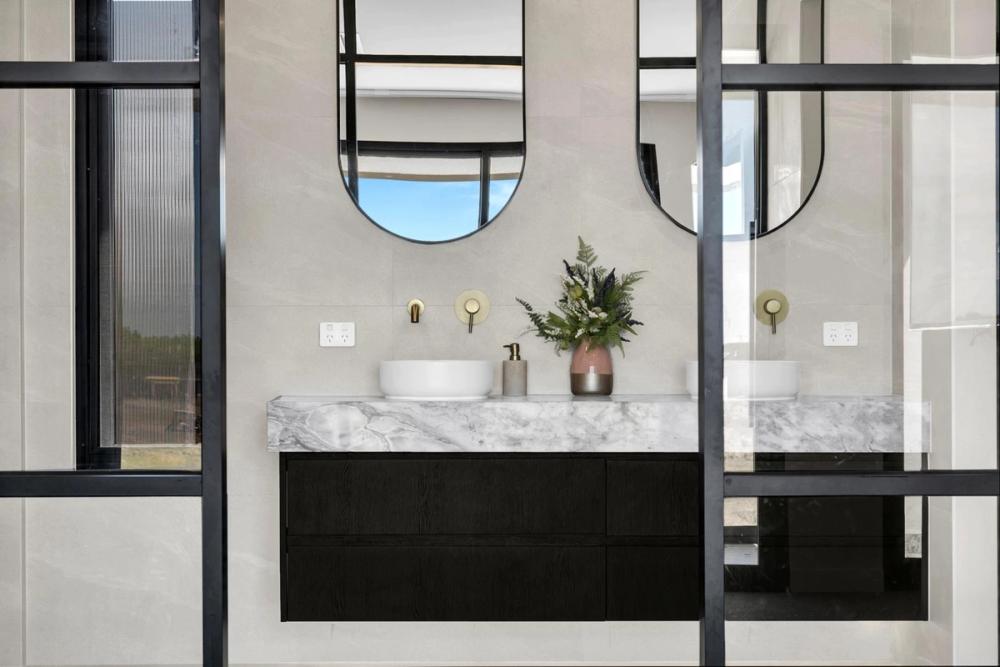 Bathroom with twin arched mirrors, a marble vanity and gold tapware, Tiffany Walk Residence, Melbourne