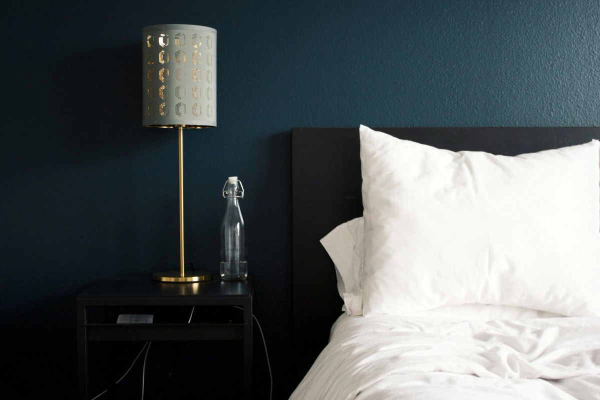 Made bed with crisp white pillows and a bedside lamp