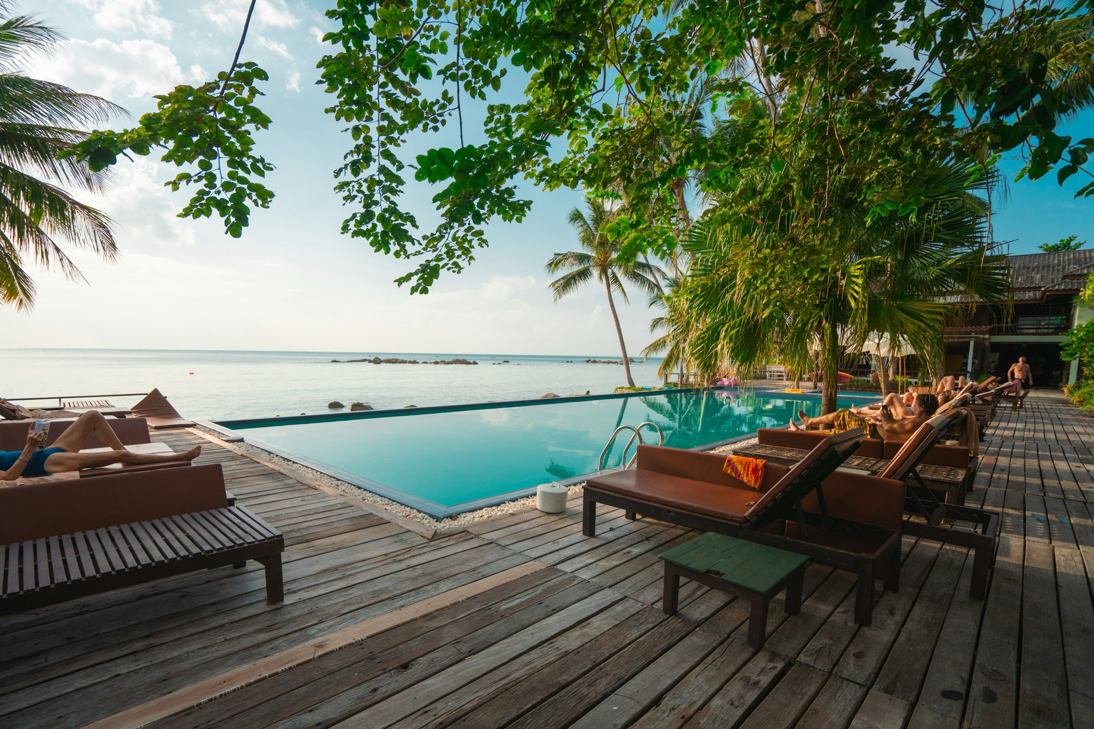Sun loungers on a deck beside an infinity pool facing the sea