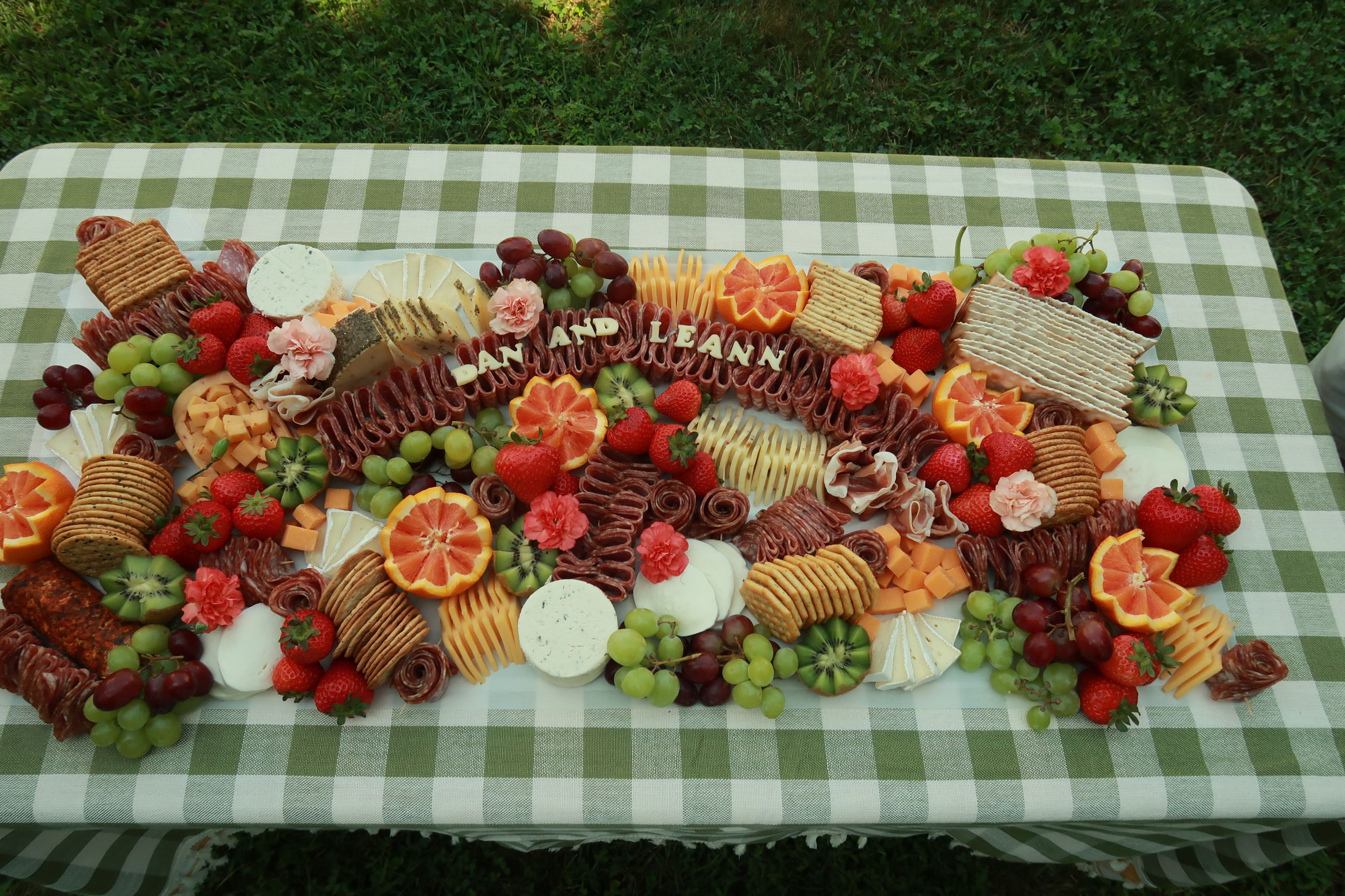 A grazing board of citrus and grapes on green gingham
