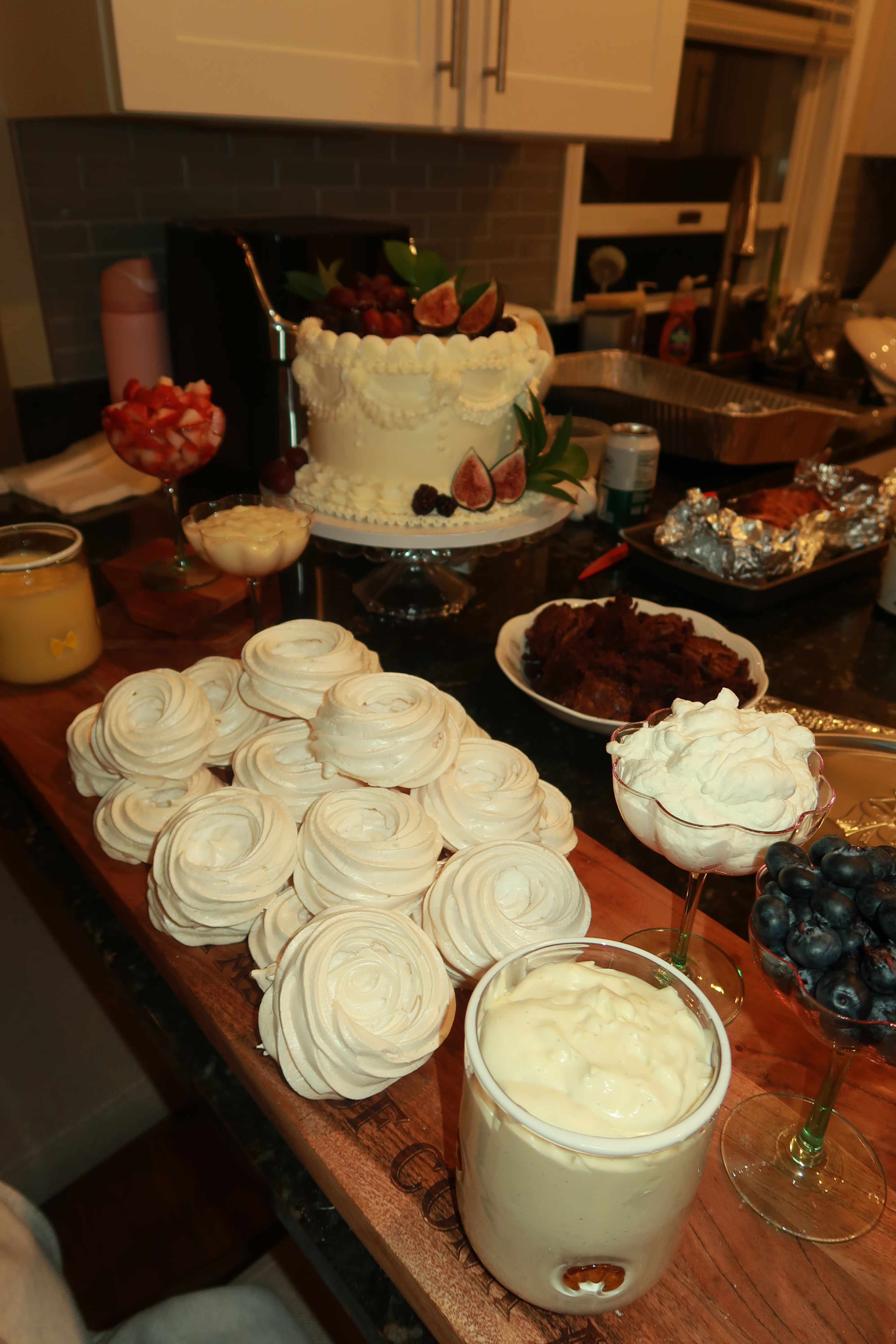 A dessert table with a tiered cake and meringues