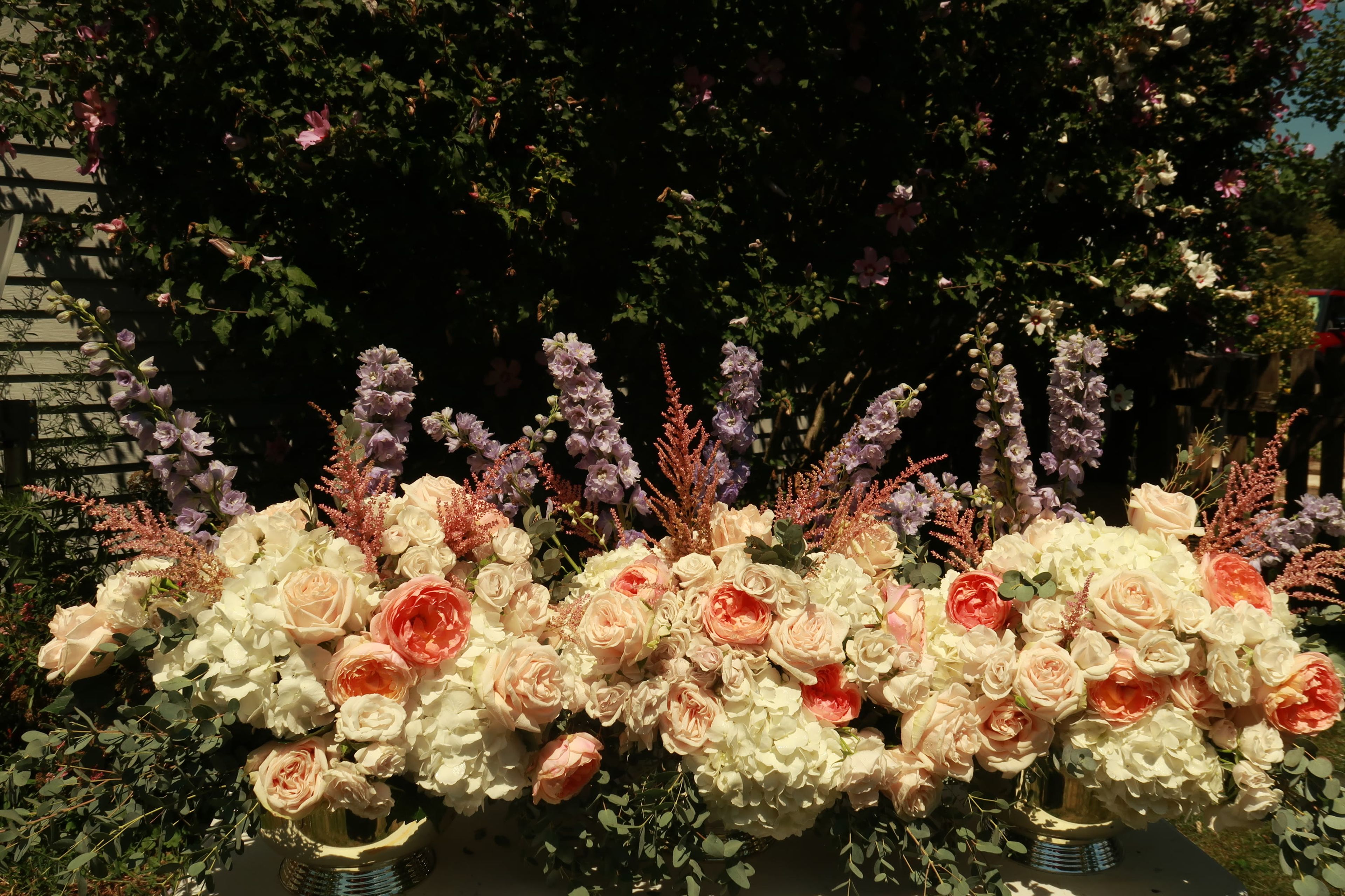 A peach and cream arrangement of garden roses and larkspur