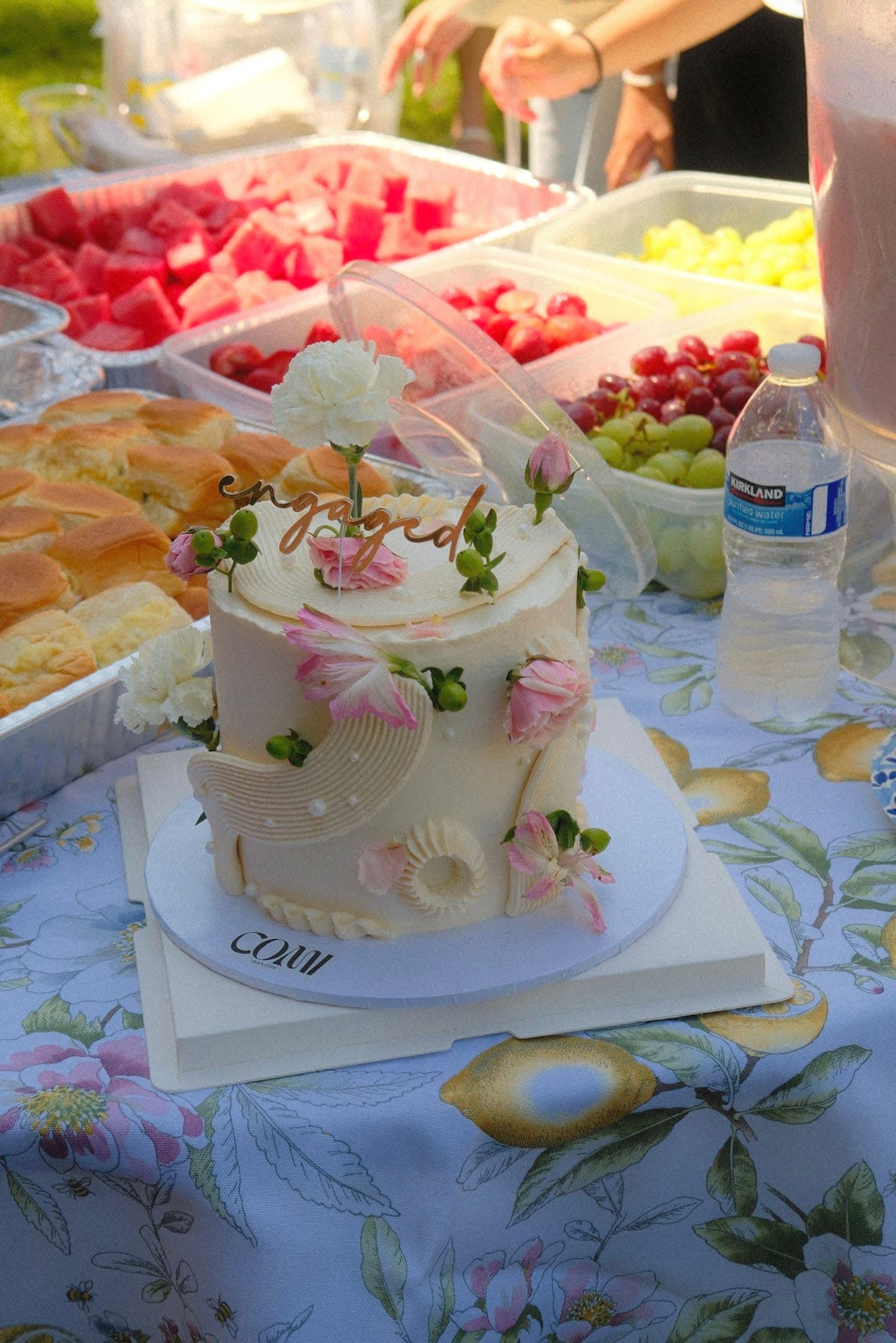 A tiered cake trimmed with pink flowers on a dessert table