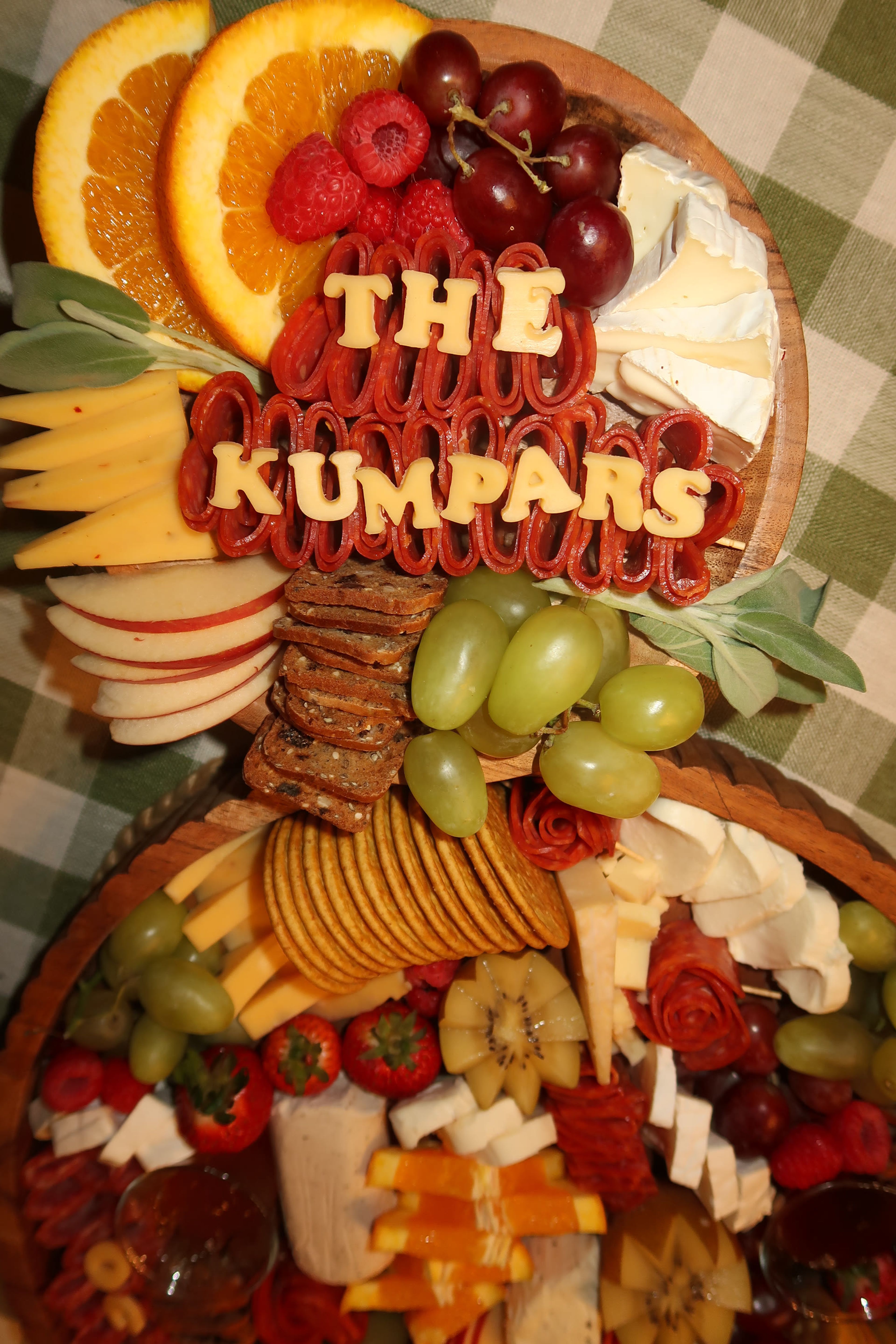 A round board with fanned cheese and apple slices, lettered 'The Kumpars'