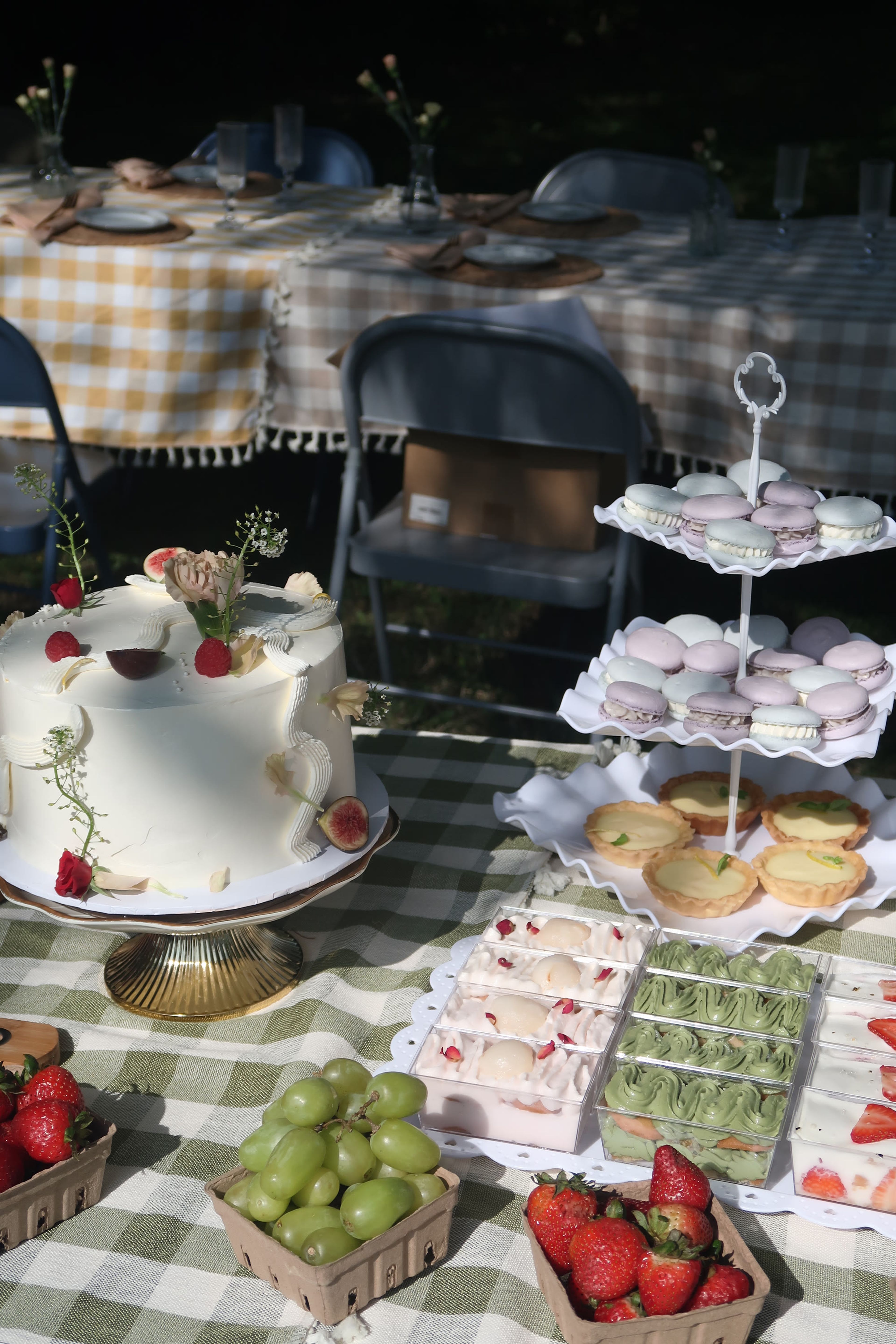A frosted cake and meringues on a green gingham table