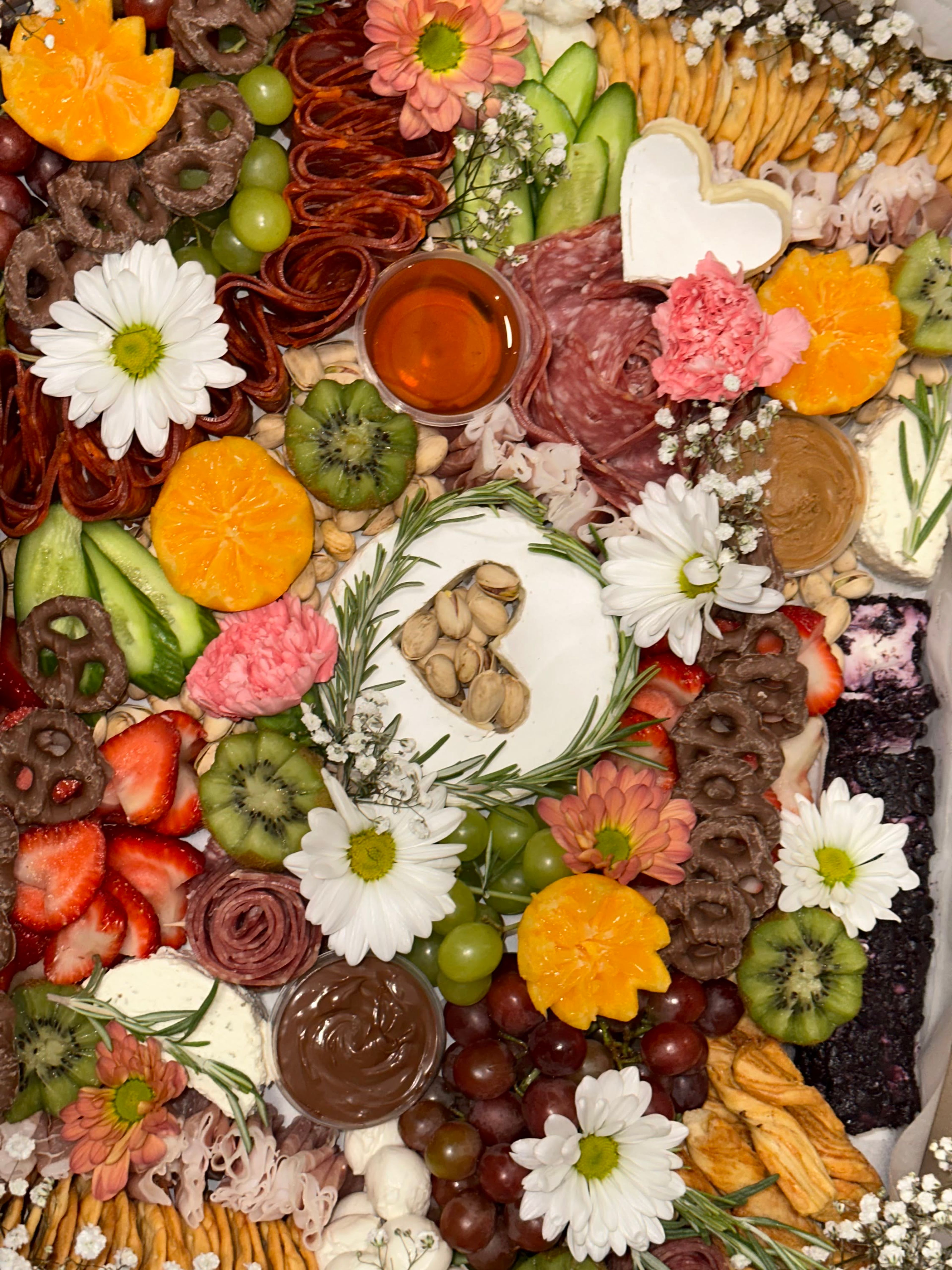 An overhead board of daisies and cured meat roses