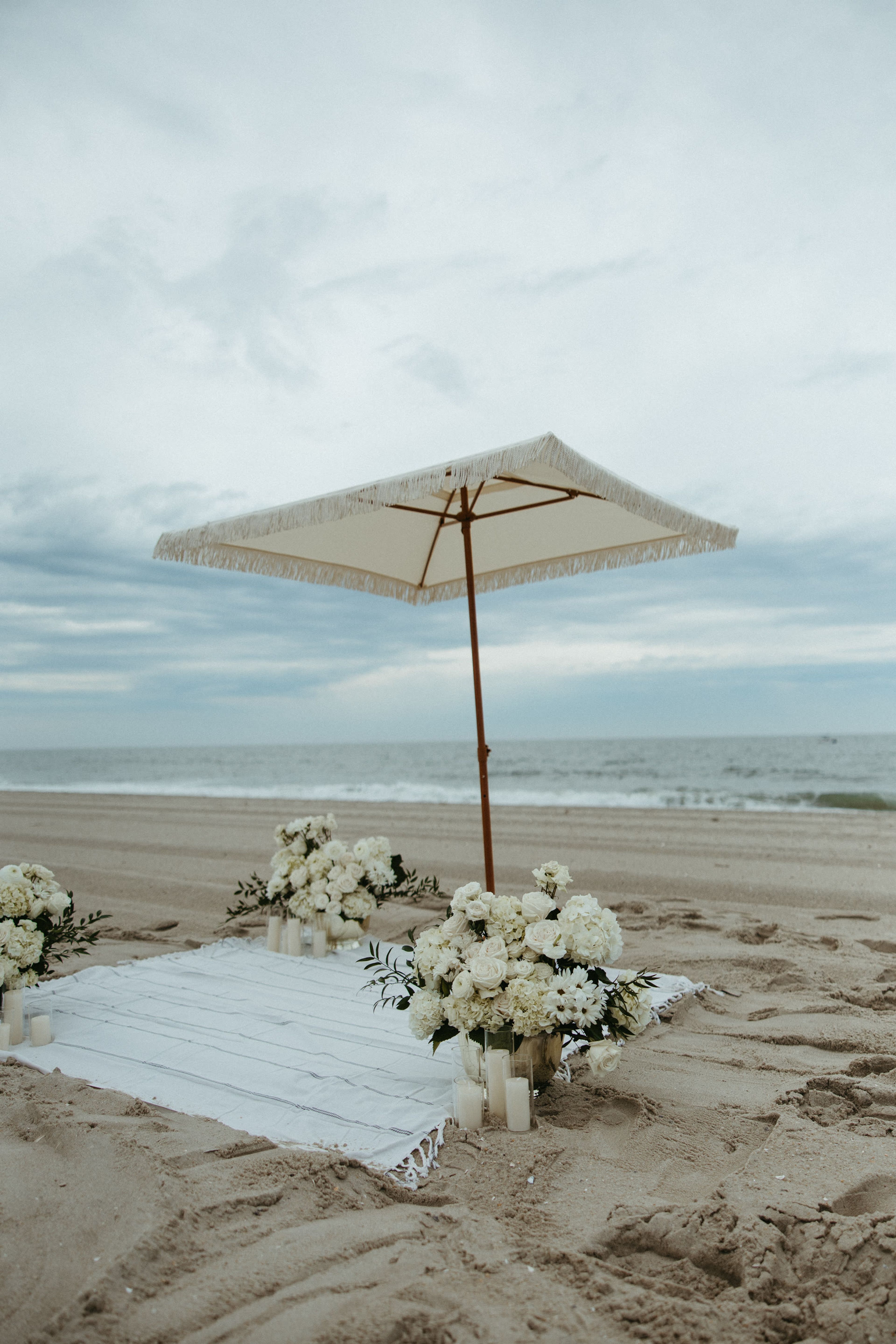 A parasol shading white flowers on the beach