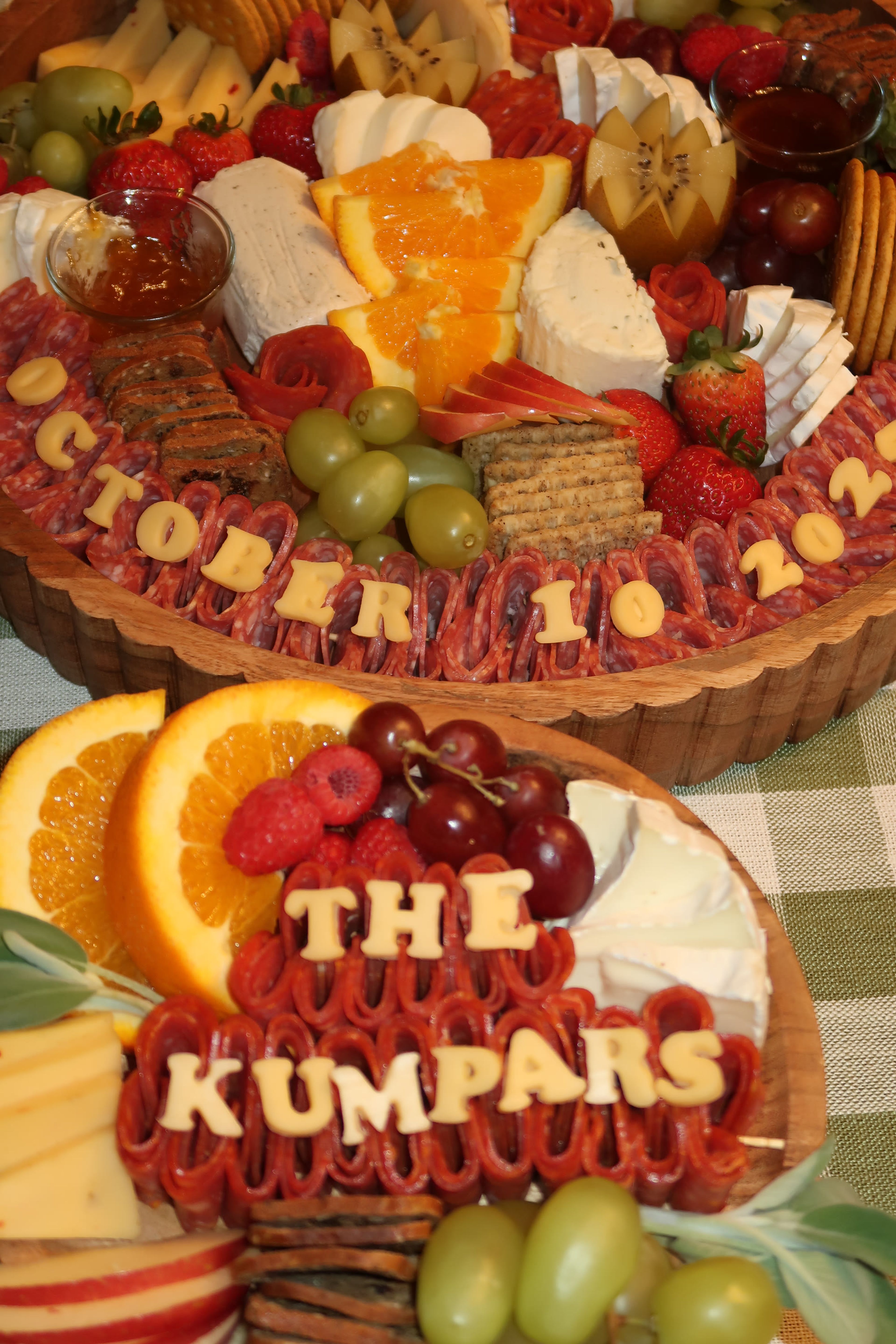 An overhead round board of crackers, cheeses and fresh fruit