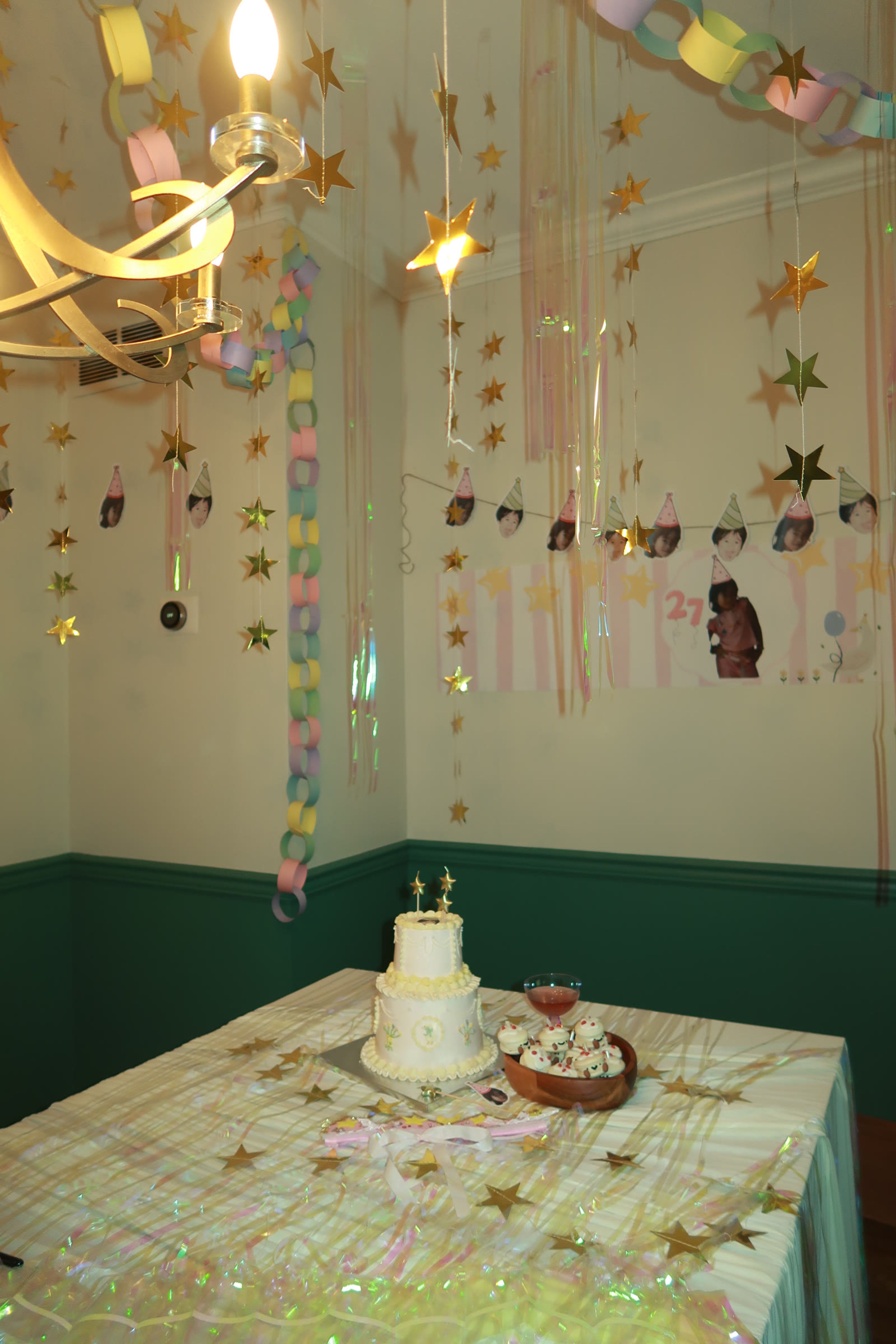A cake table framed by paper streamers and hanging photographs
