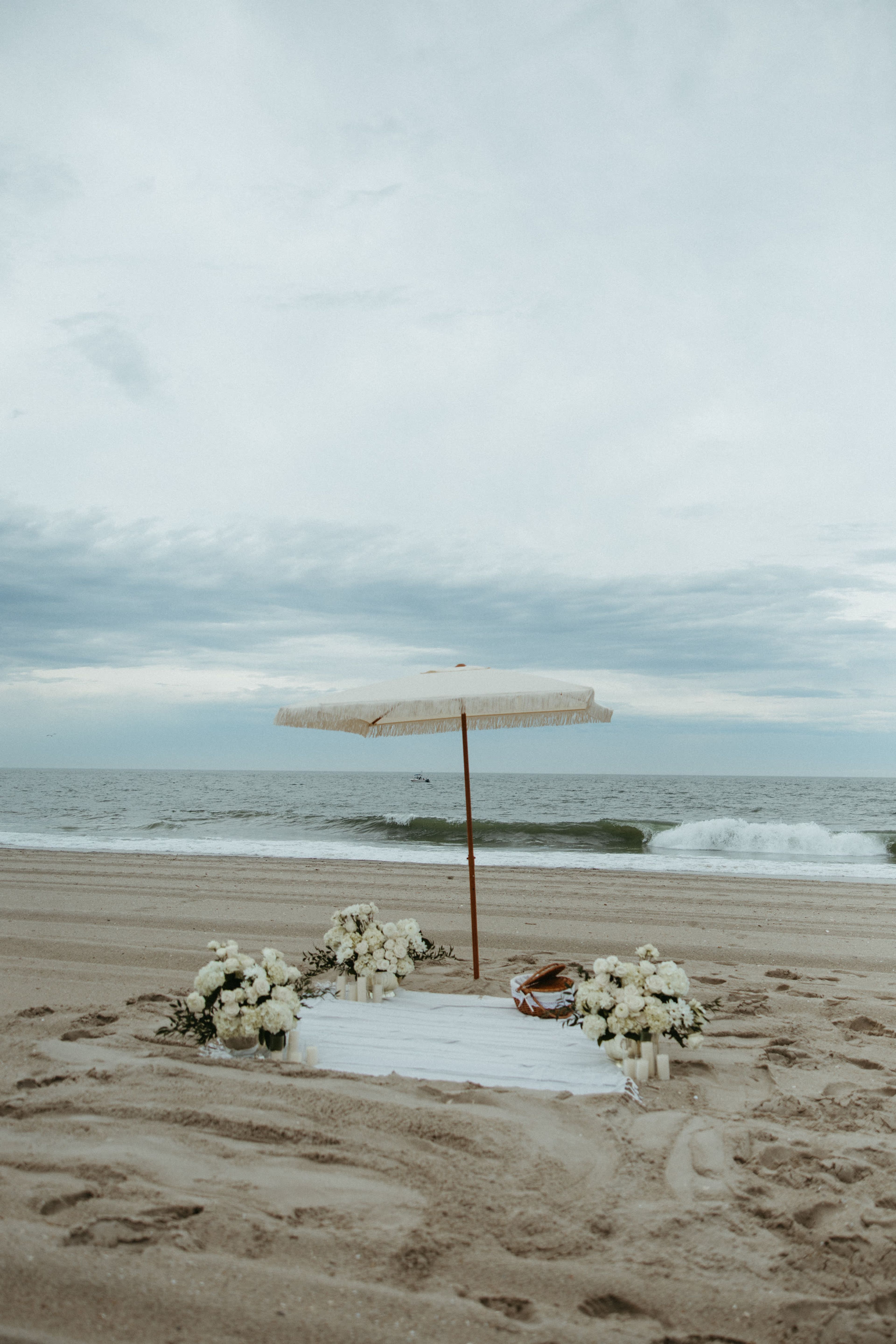 A parasol and white florals set up at the shoreline
