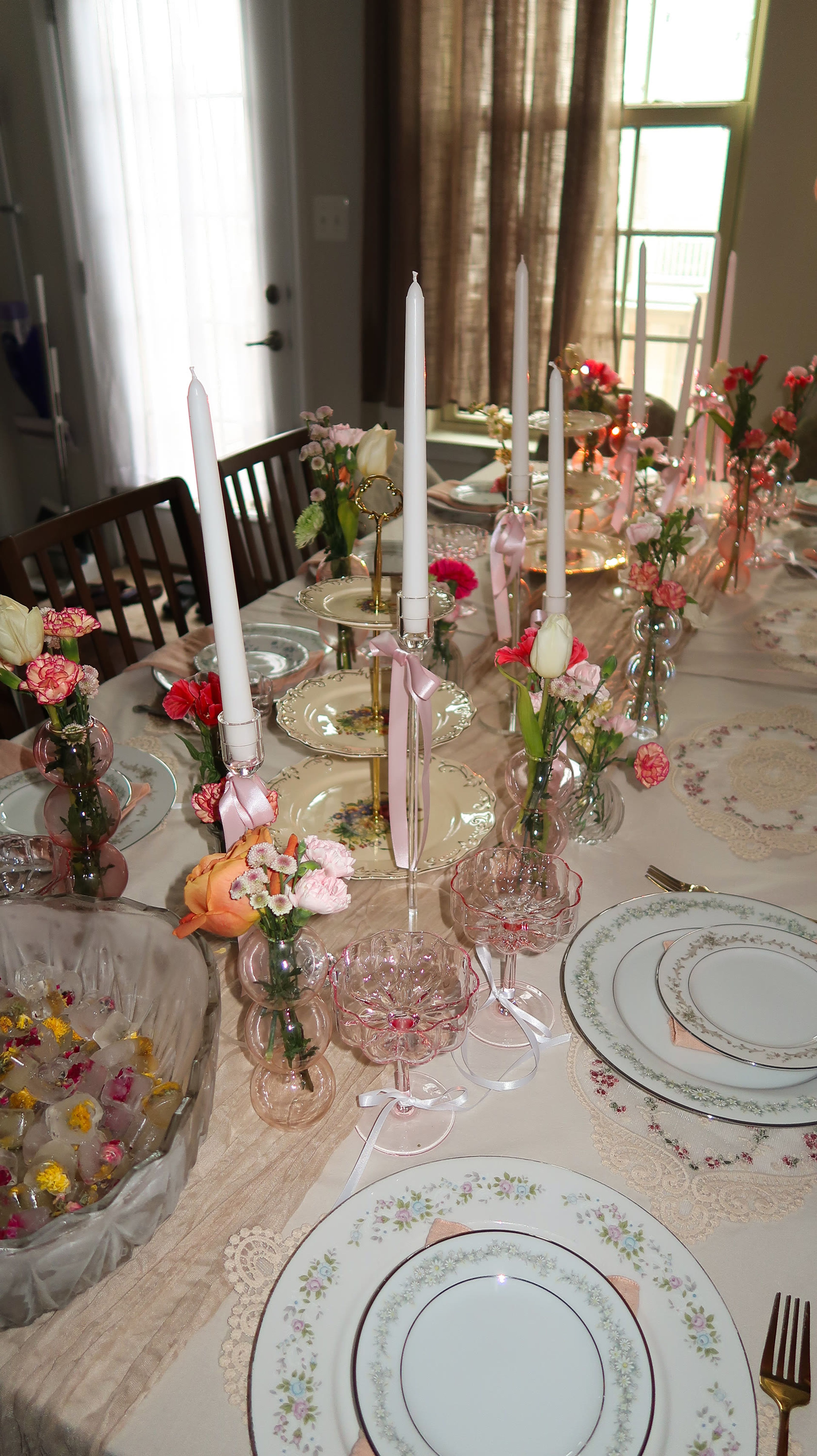 A table set with pink florals, candles and crystal