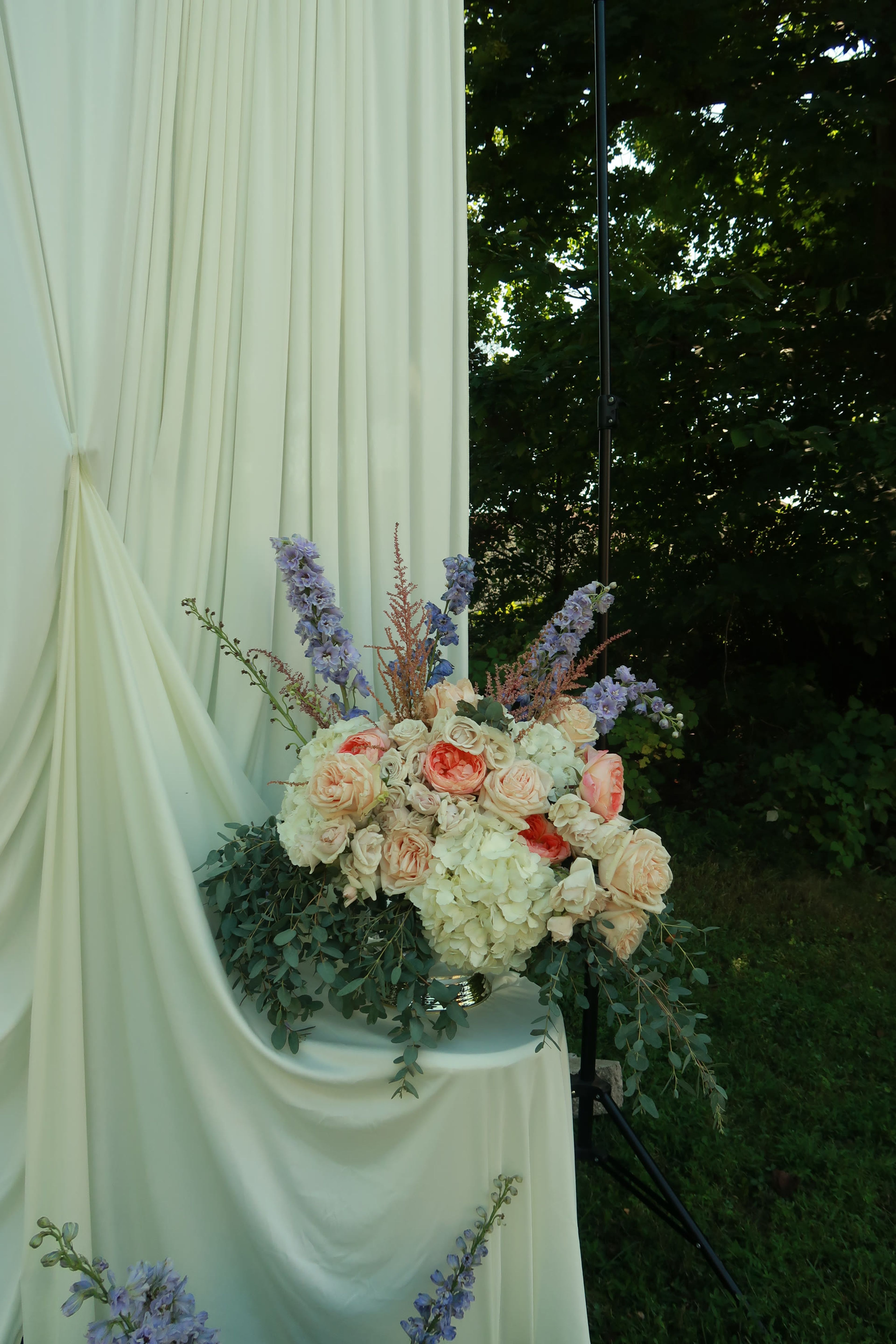 Cream drapery framing roses, hydrangea and dusty miller