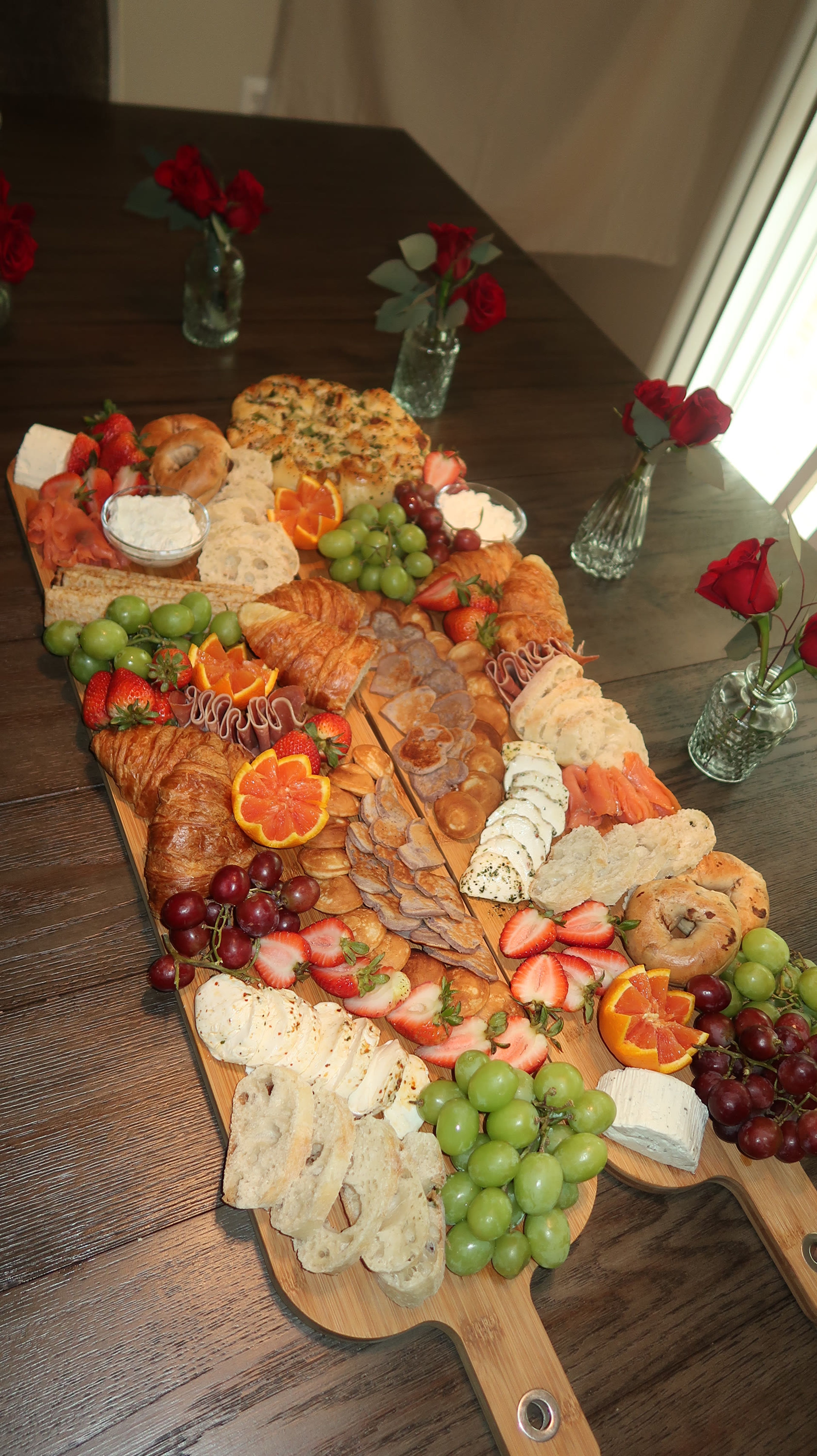 A long grazing board of citrus and florals on a wooden table
