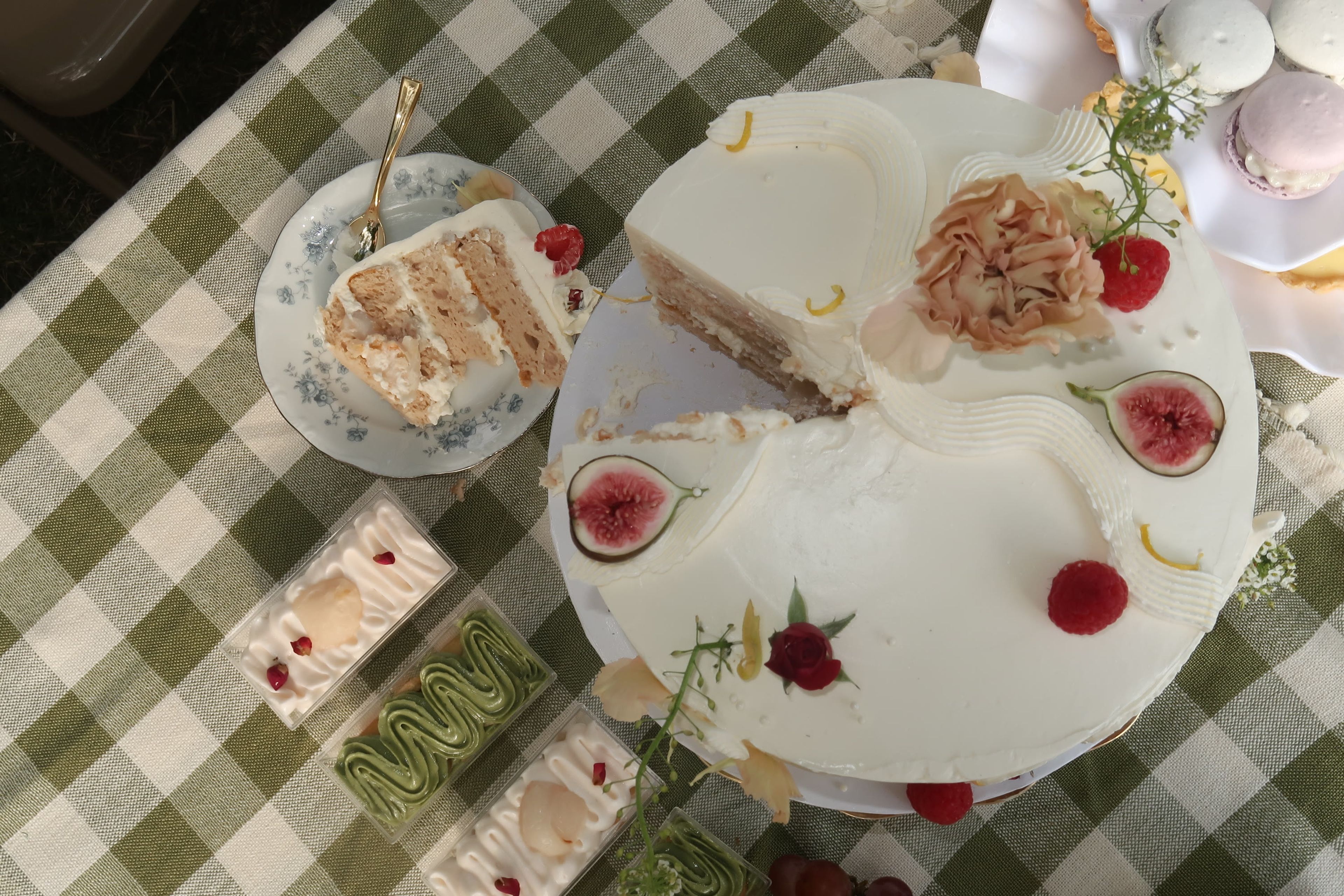 An overhead view of a sliced layer cake with figs and berries