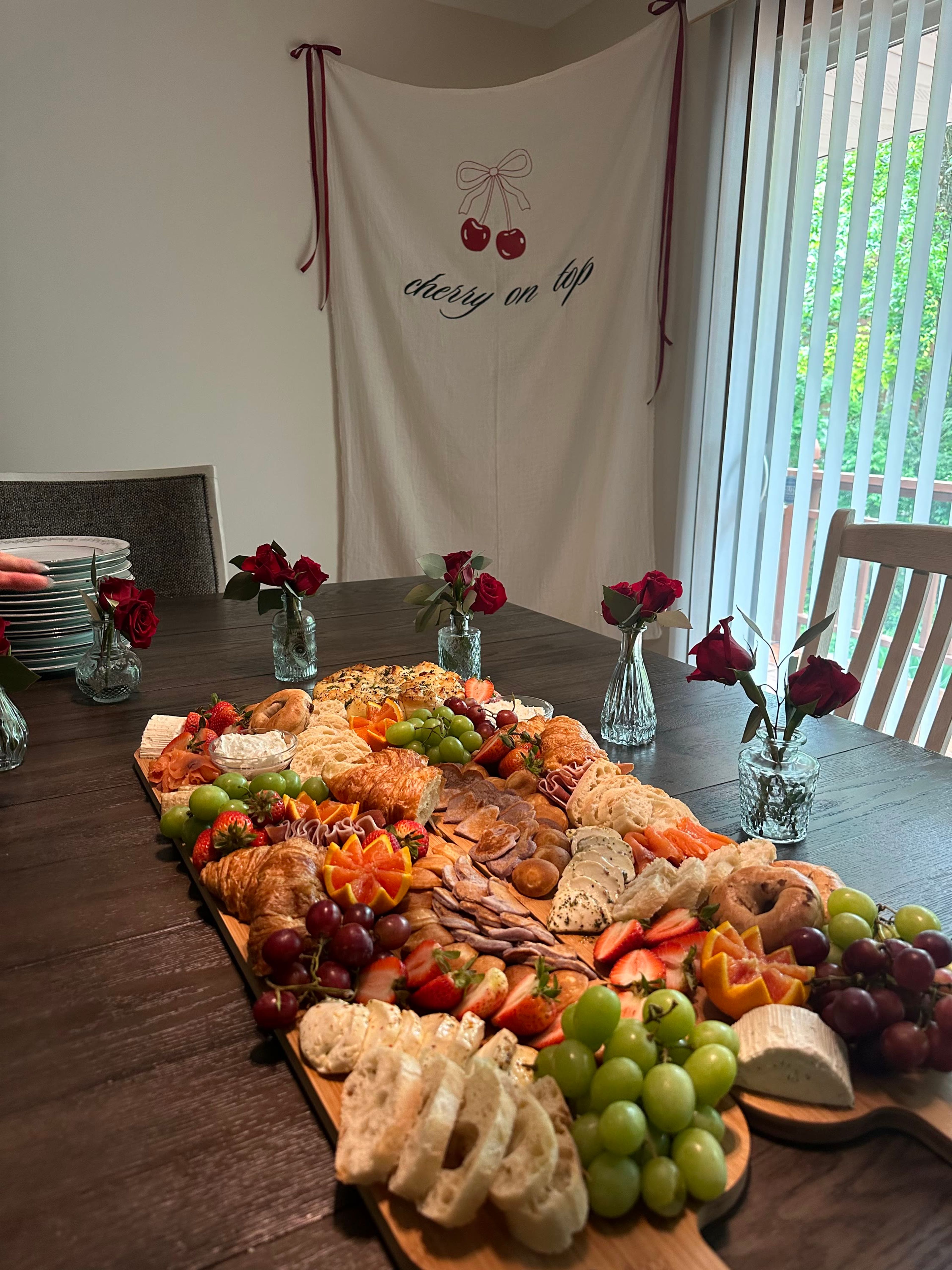 A long board with red roses on a wooden dining table