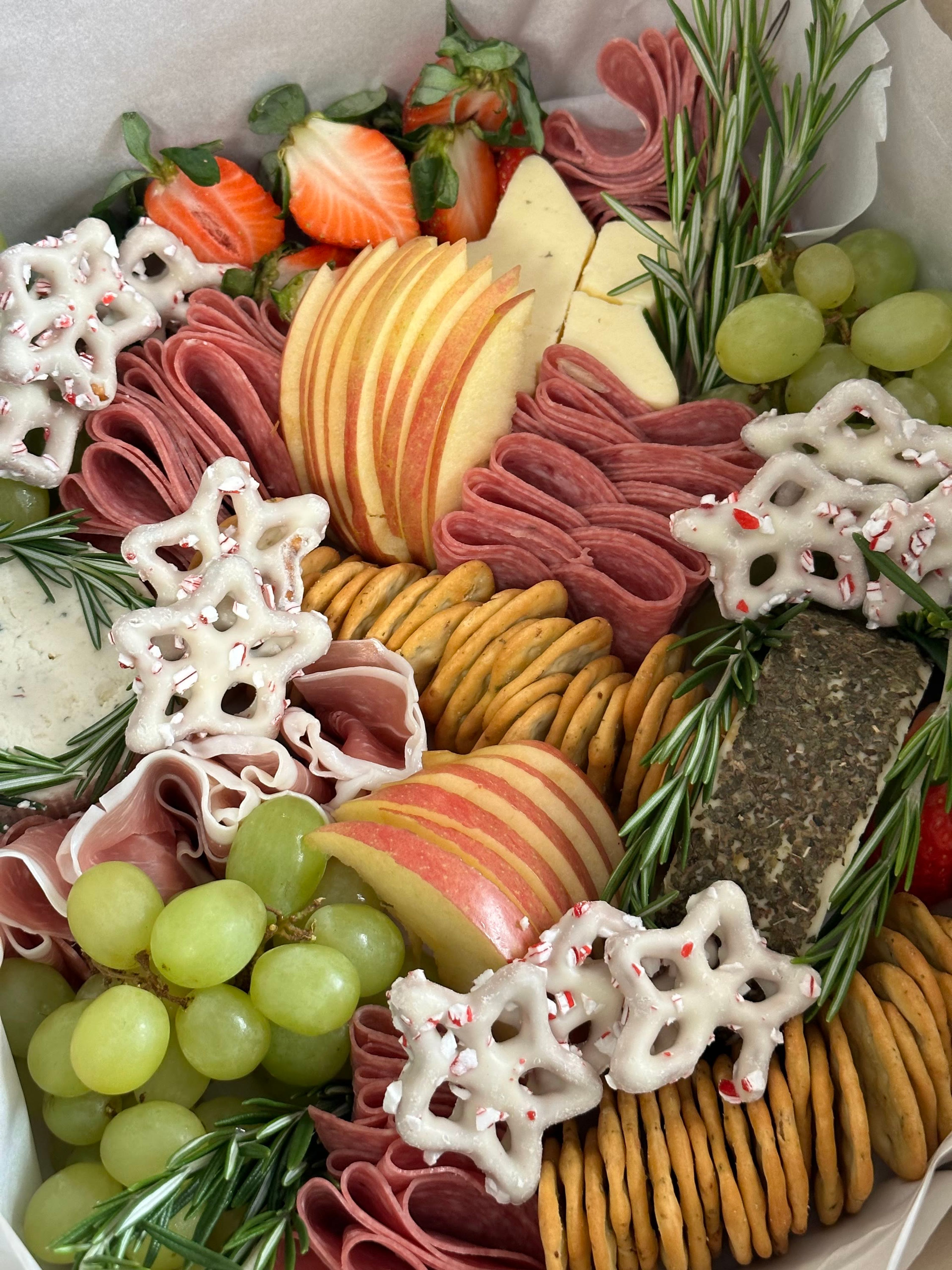 An overhead board of pretzels, apple, rosemary and cured meats