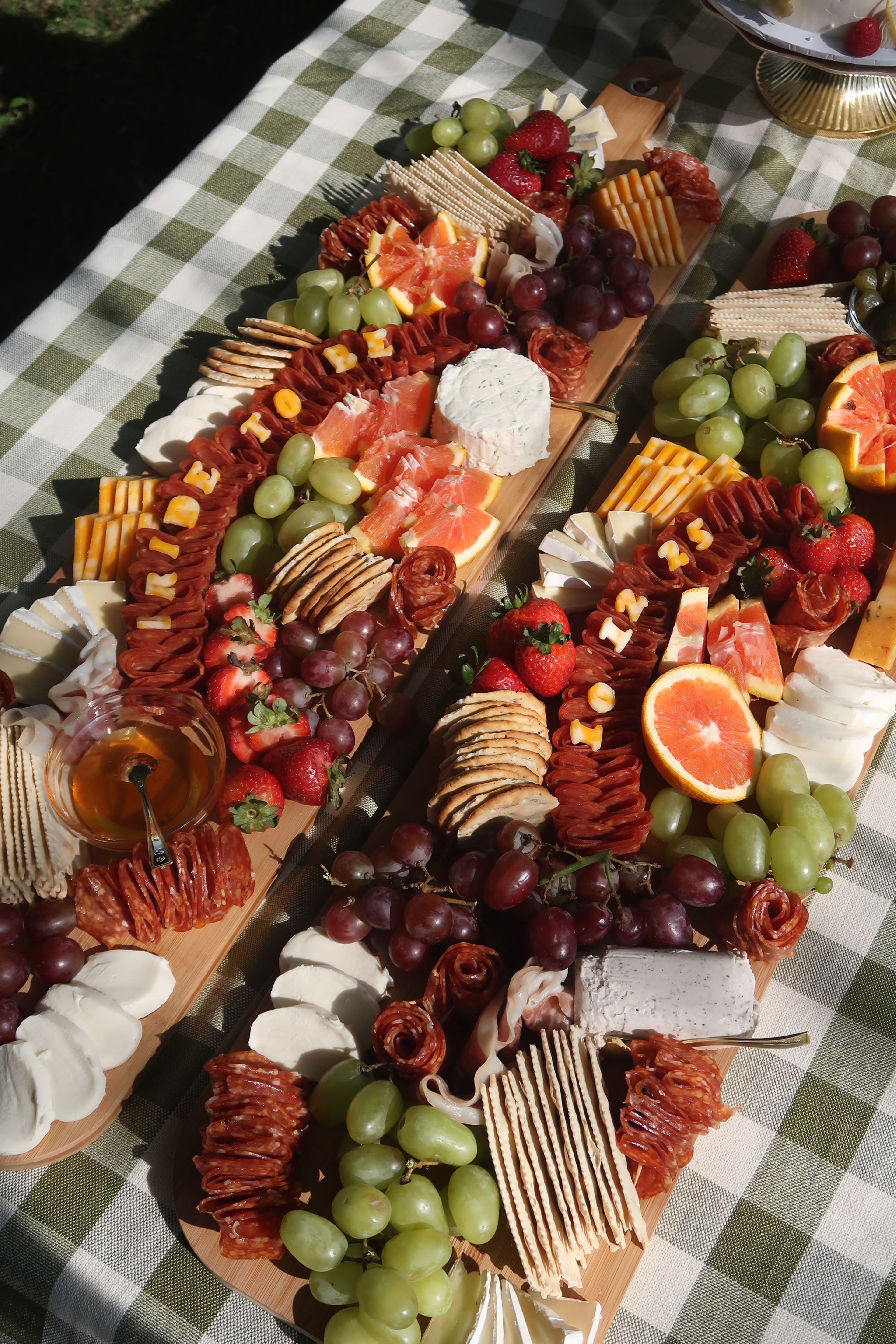 A long grazing board of citrus and cured meats in diagonal sunlight