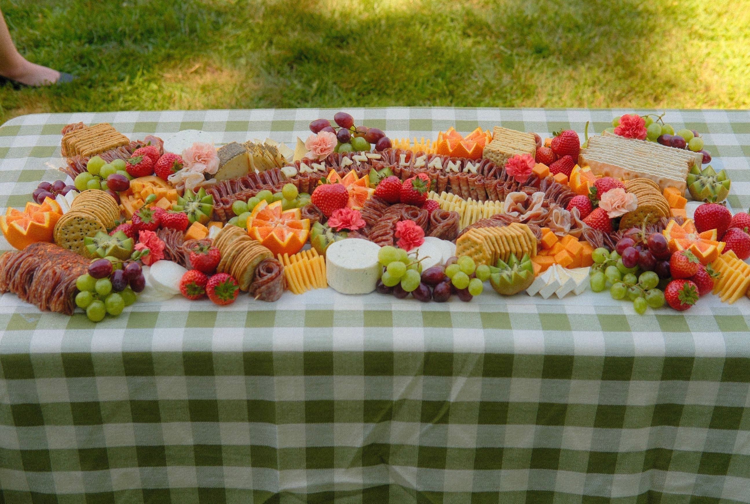 A lettered grazing board running the length of a gingham table