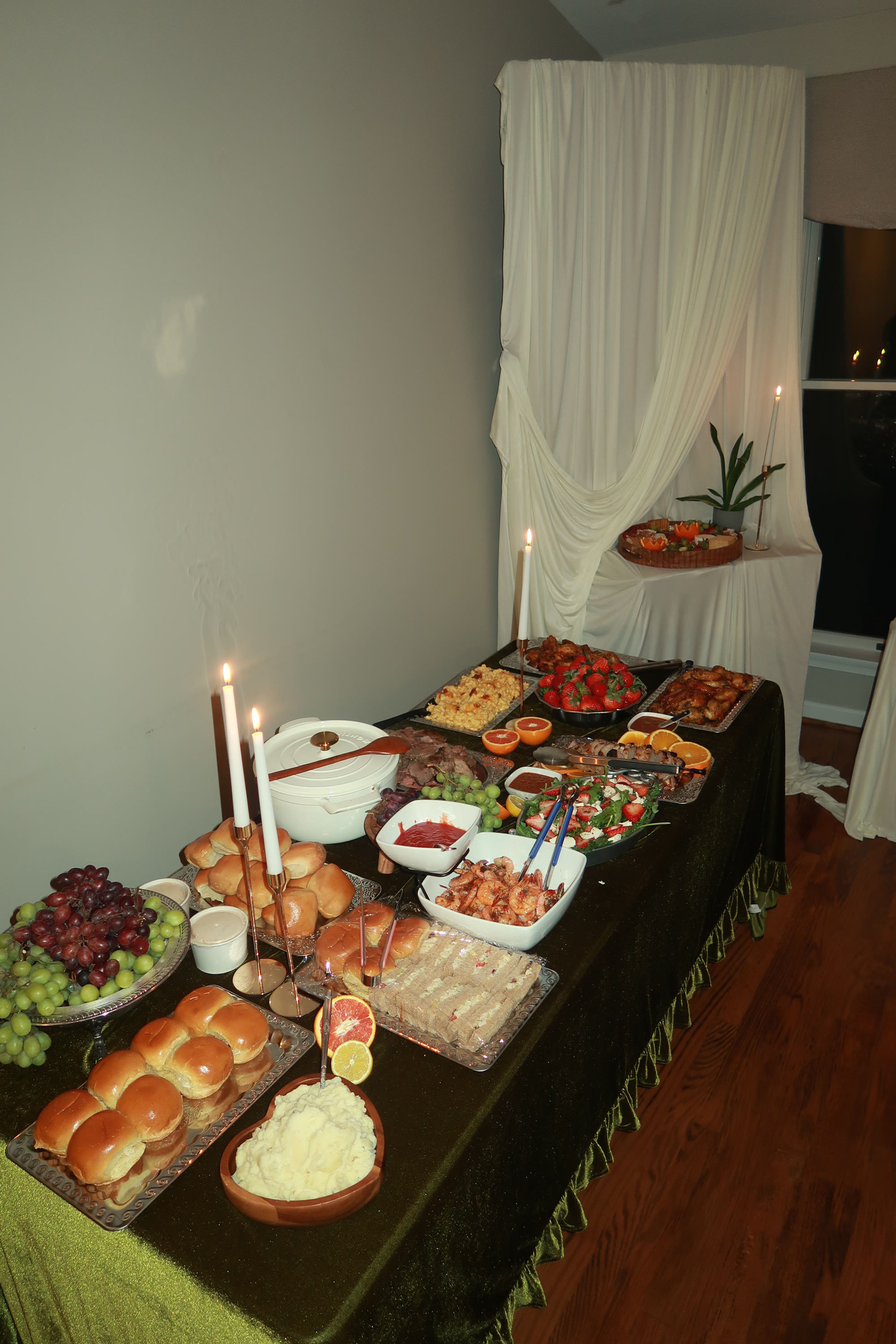 A candlelit buffet table laid end to end with breads, fruit and platters