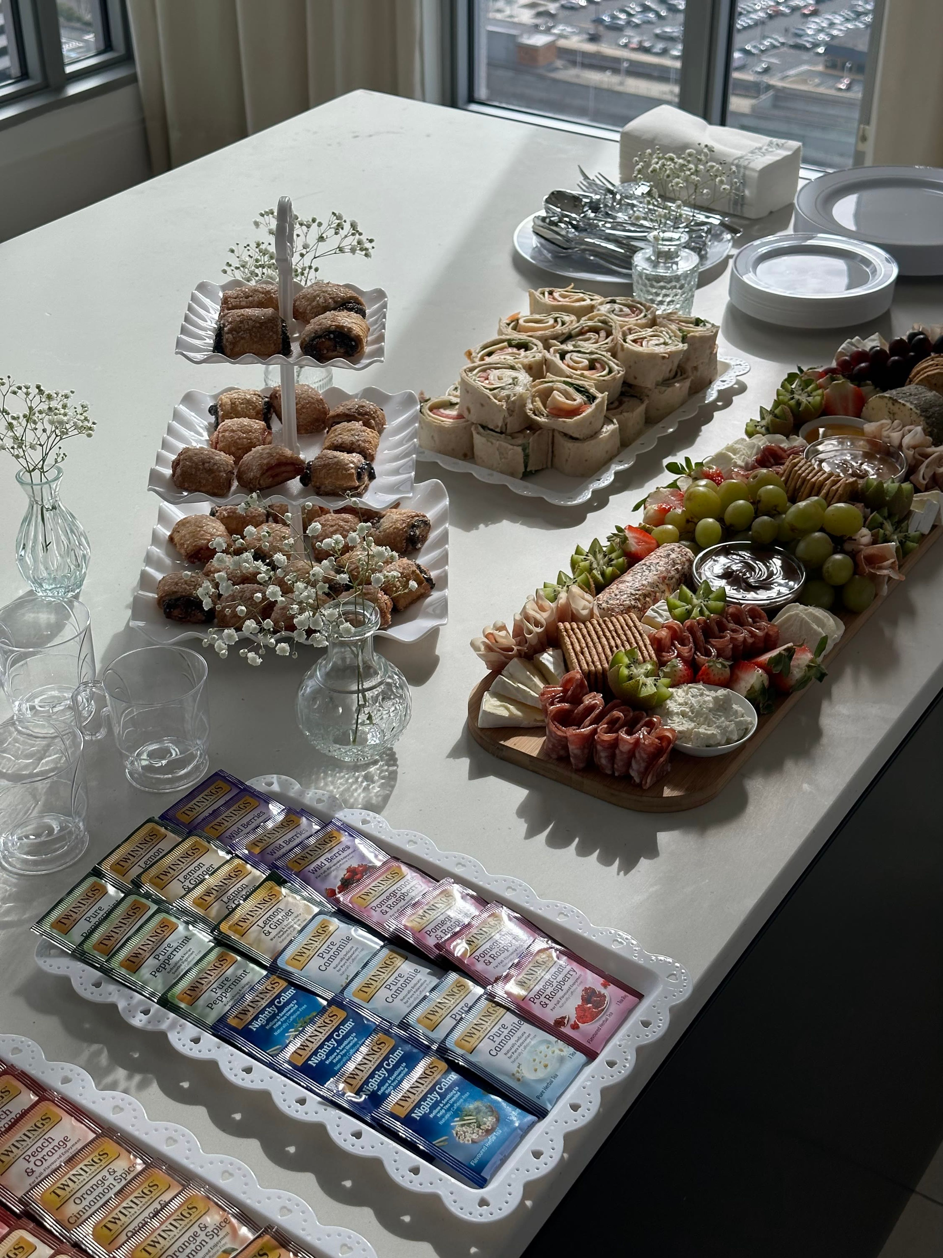 A buffet of sandwiches, pastries and grazing boards on a white table