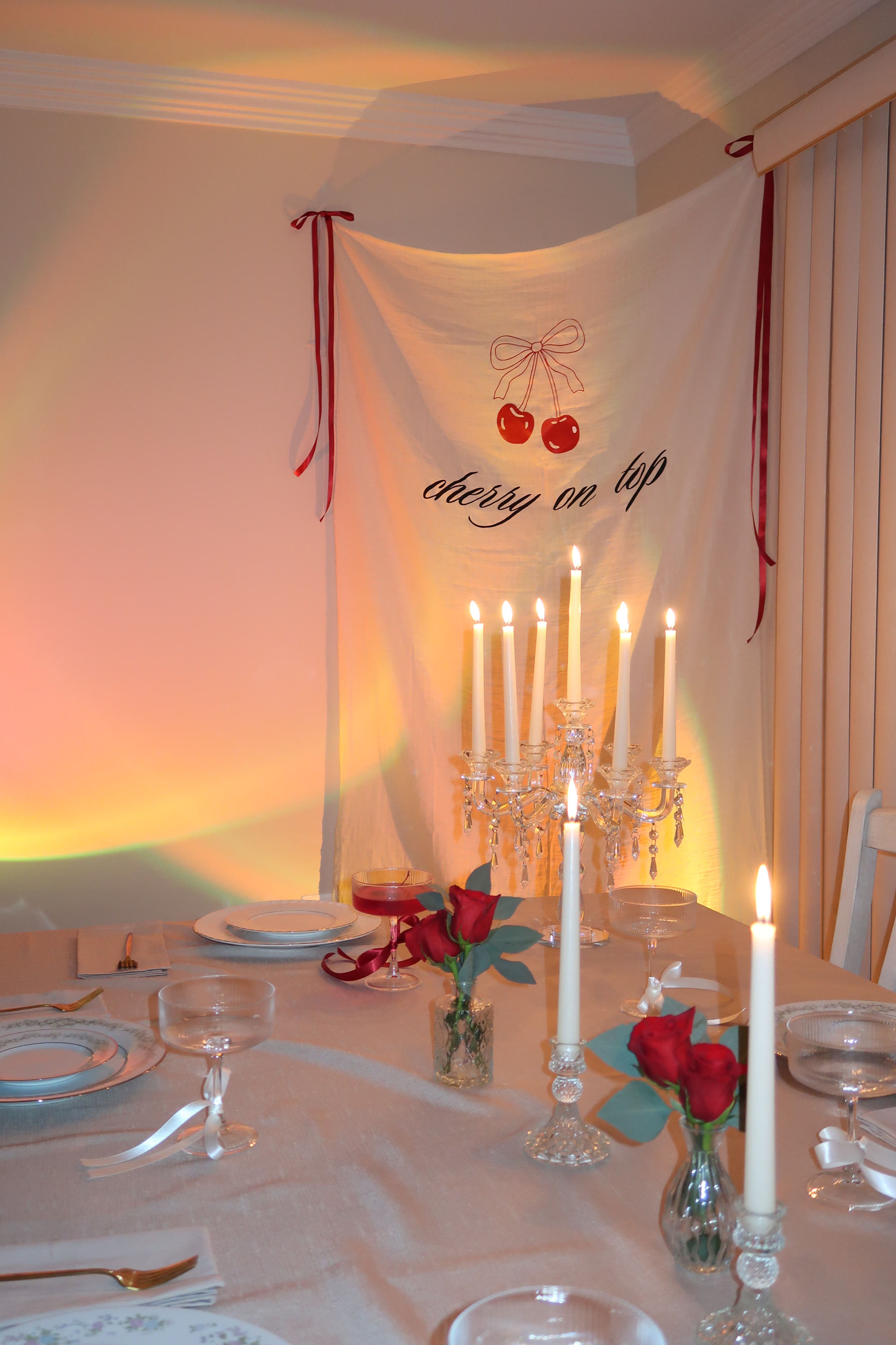 A cherry-themed banner above a candelabra and red roses