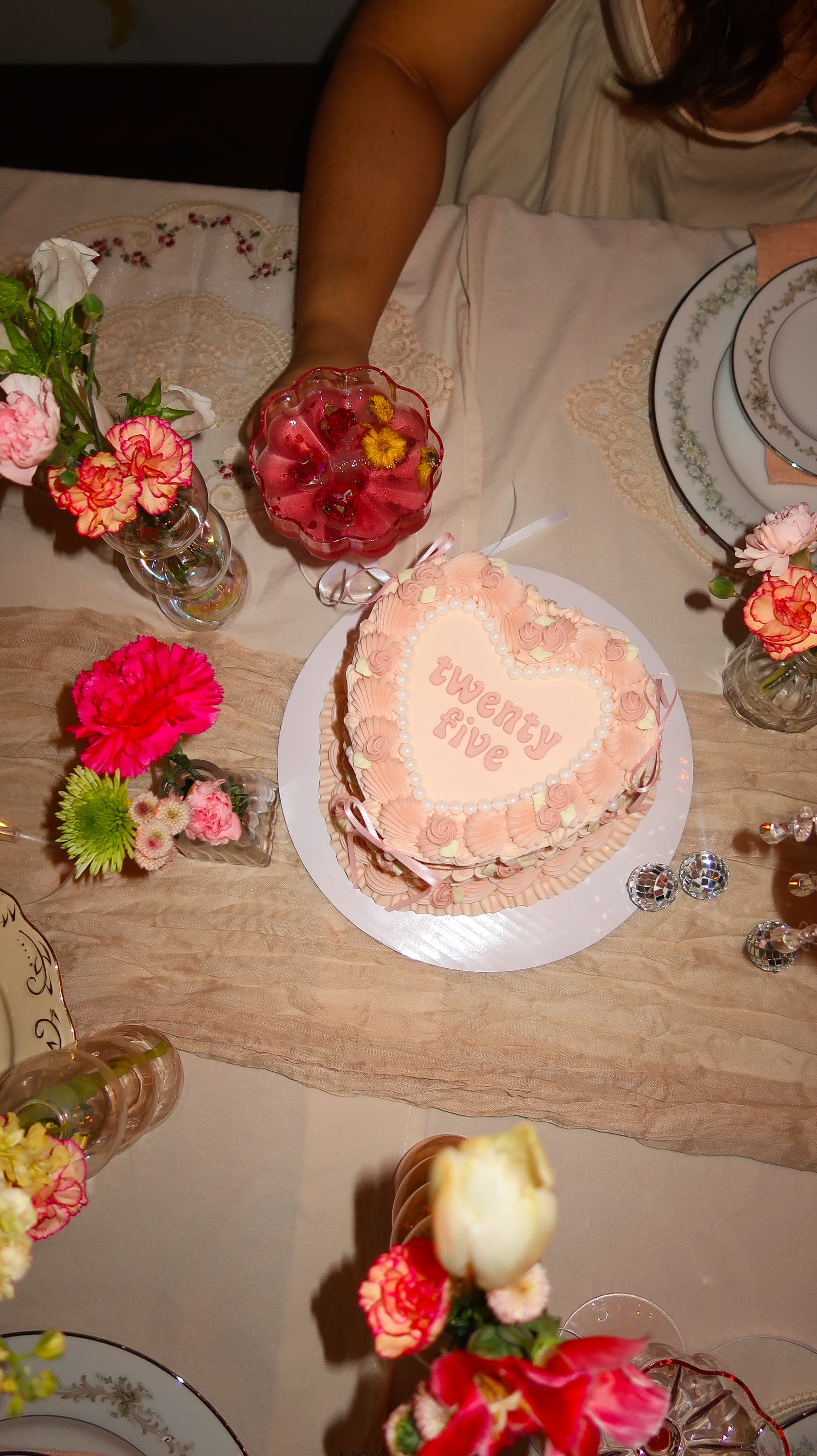 A heart-shaped cake lettered twenty five among fresh flowers