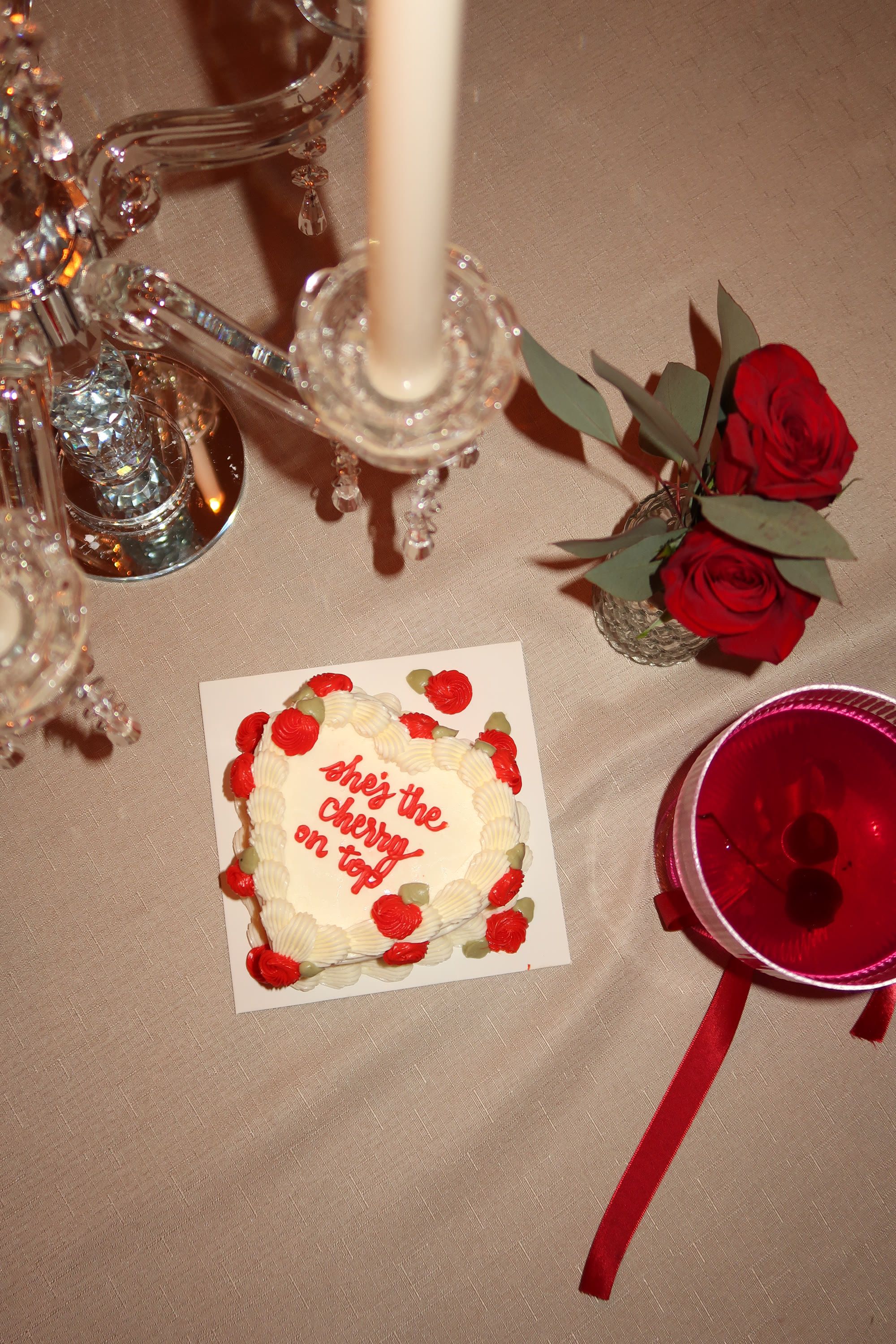 A heart-shaped cake with red roses and crystal candlesticks