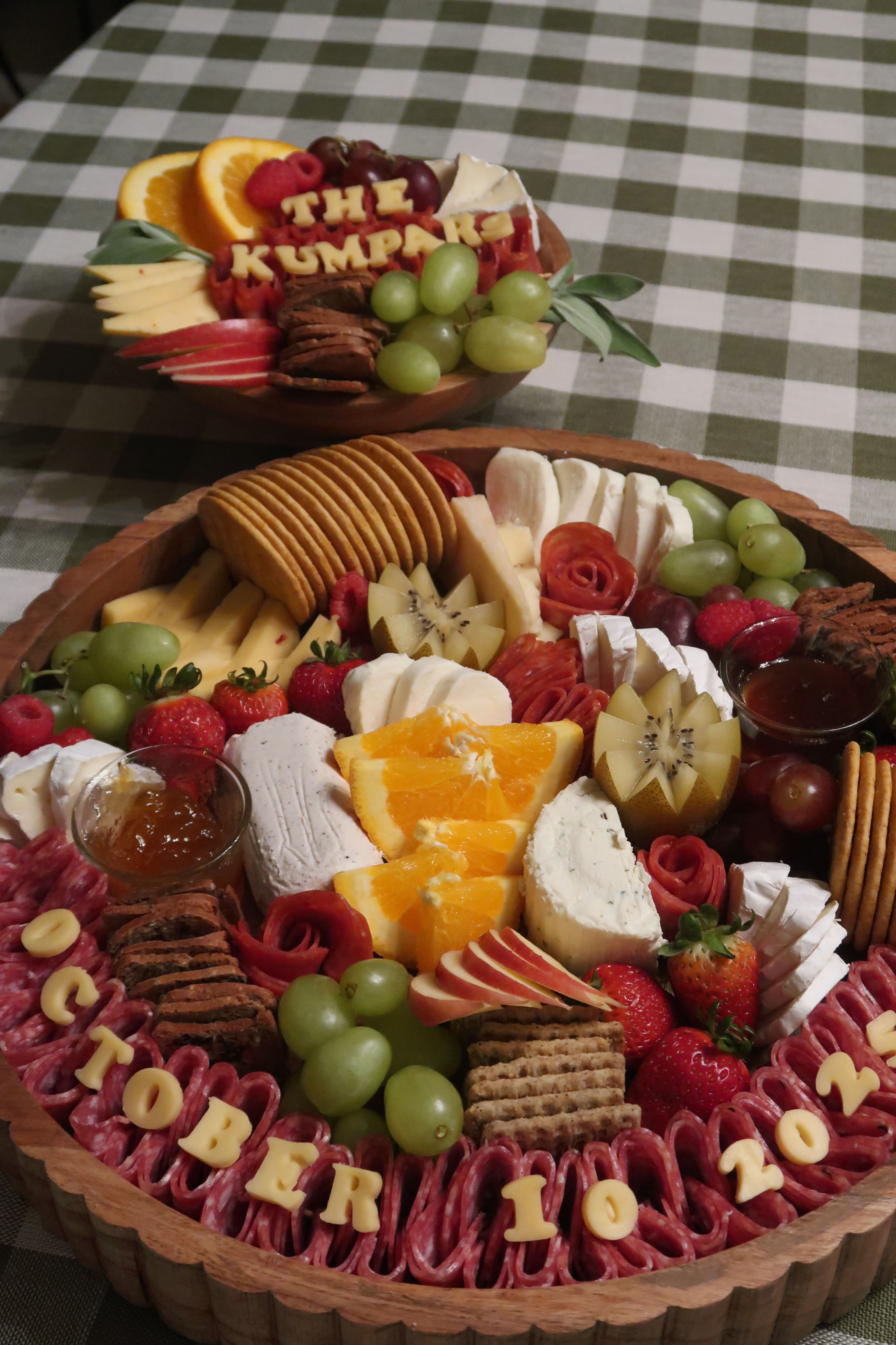 A round grazing board of crackers, cheeses and grapes