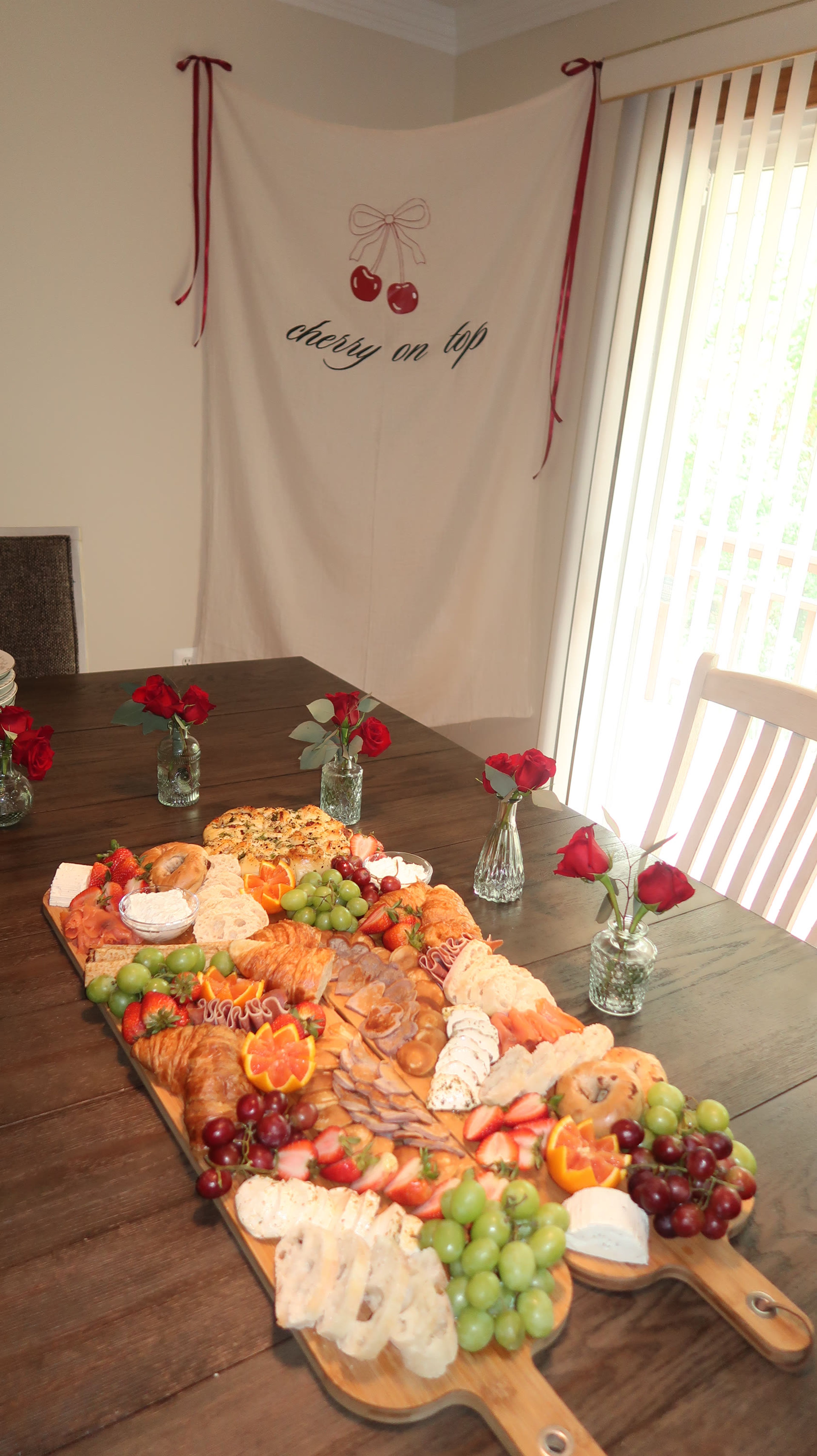 A long grazing board with roses on a wooden dining table