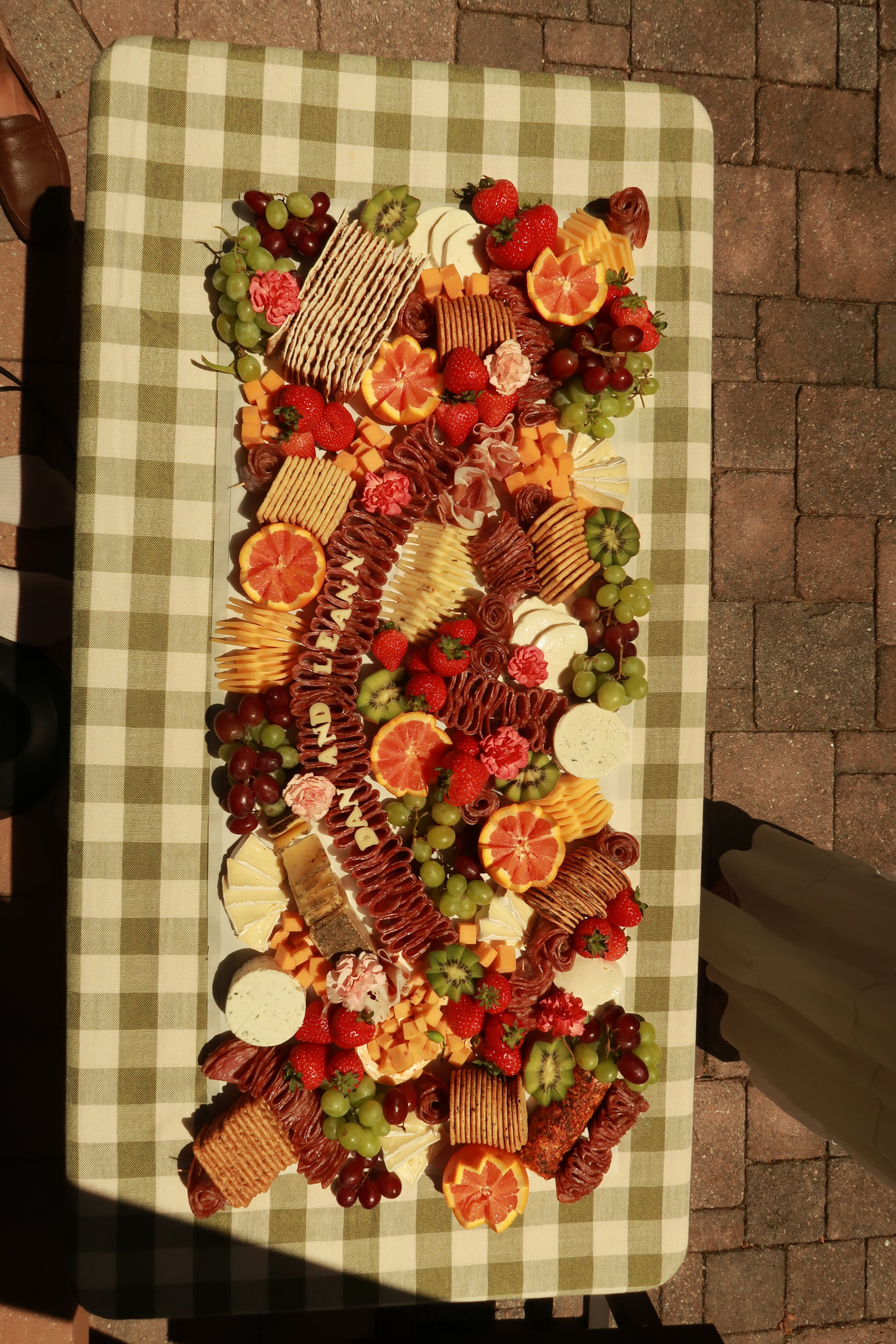 A tall grazing board of crackers, cheese and fruit