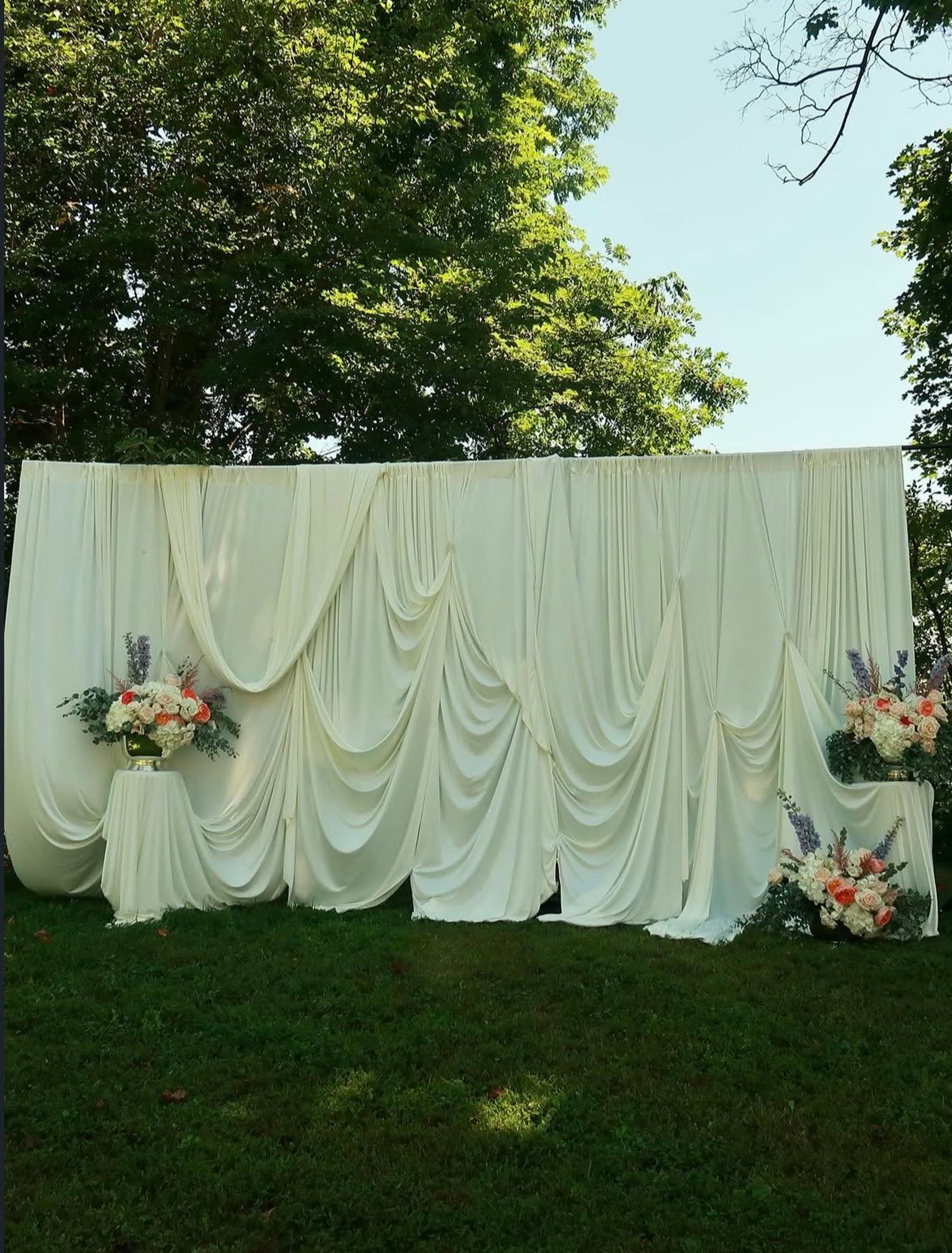 A draped backdrop with florals set up on the grass