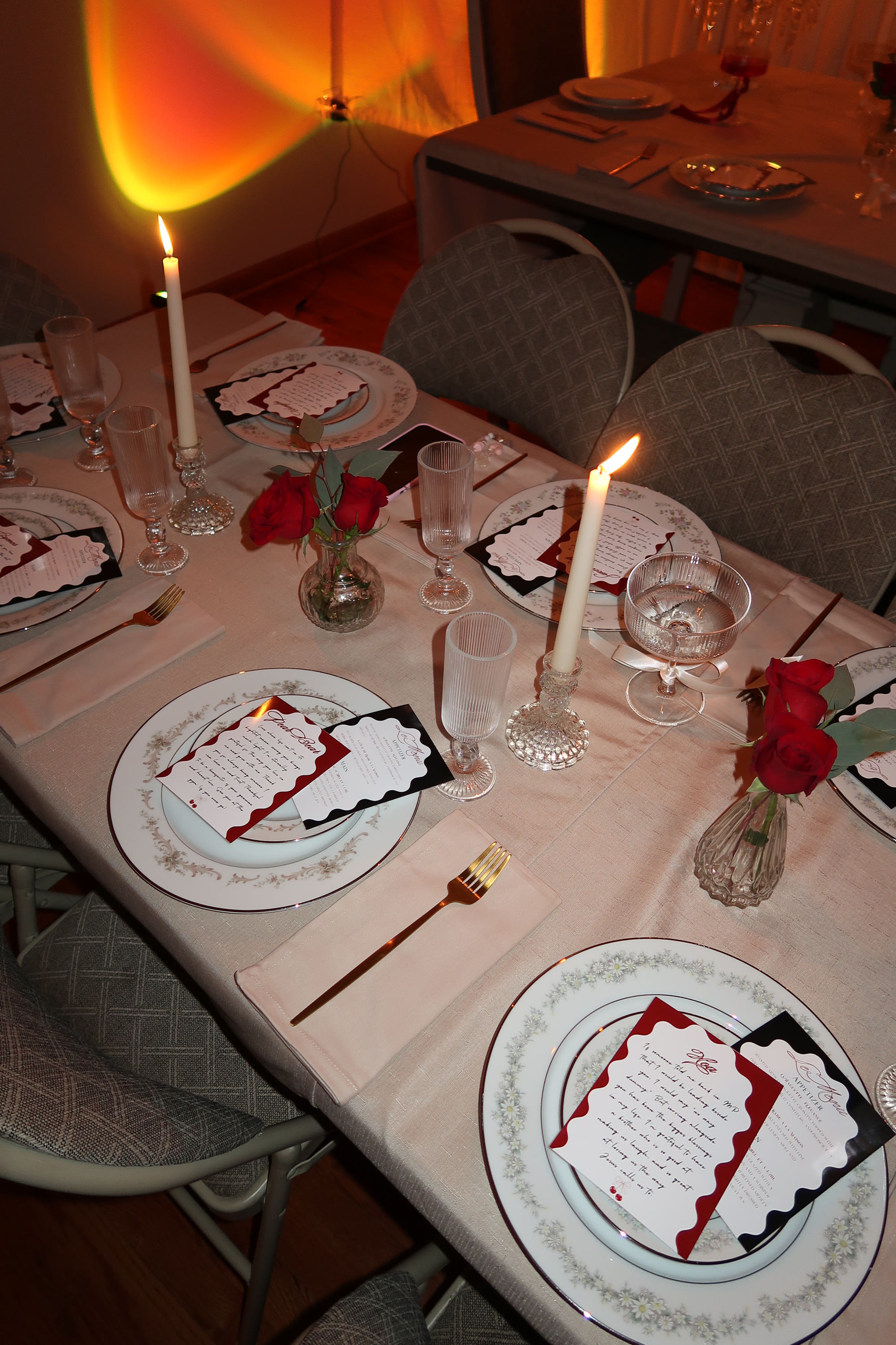 Place settings with tapered candles, crystal and red roses