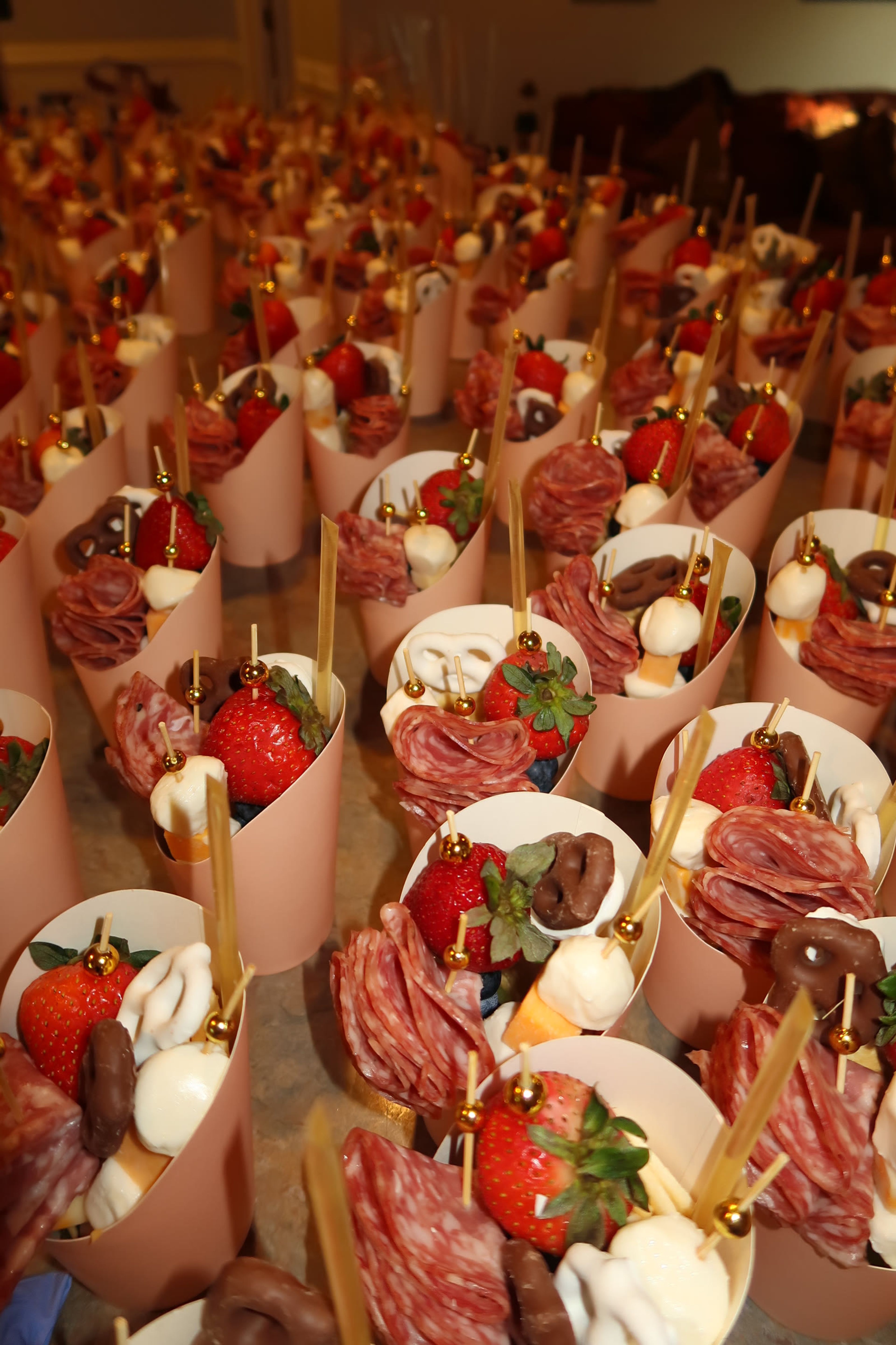A tray of charcuterie cones with strawberries and gold skewers