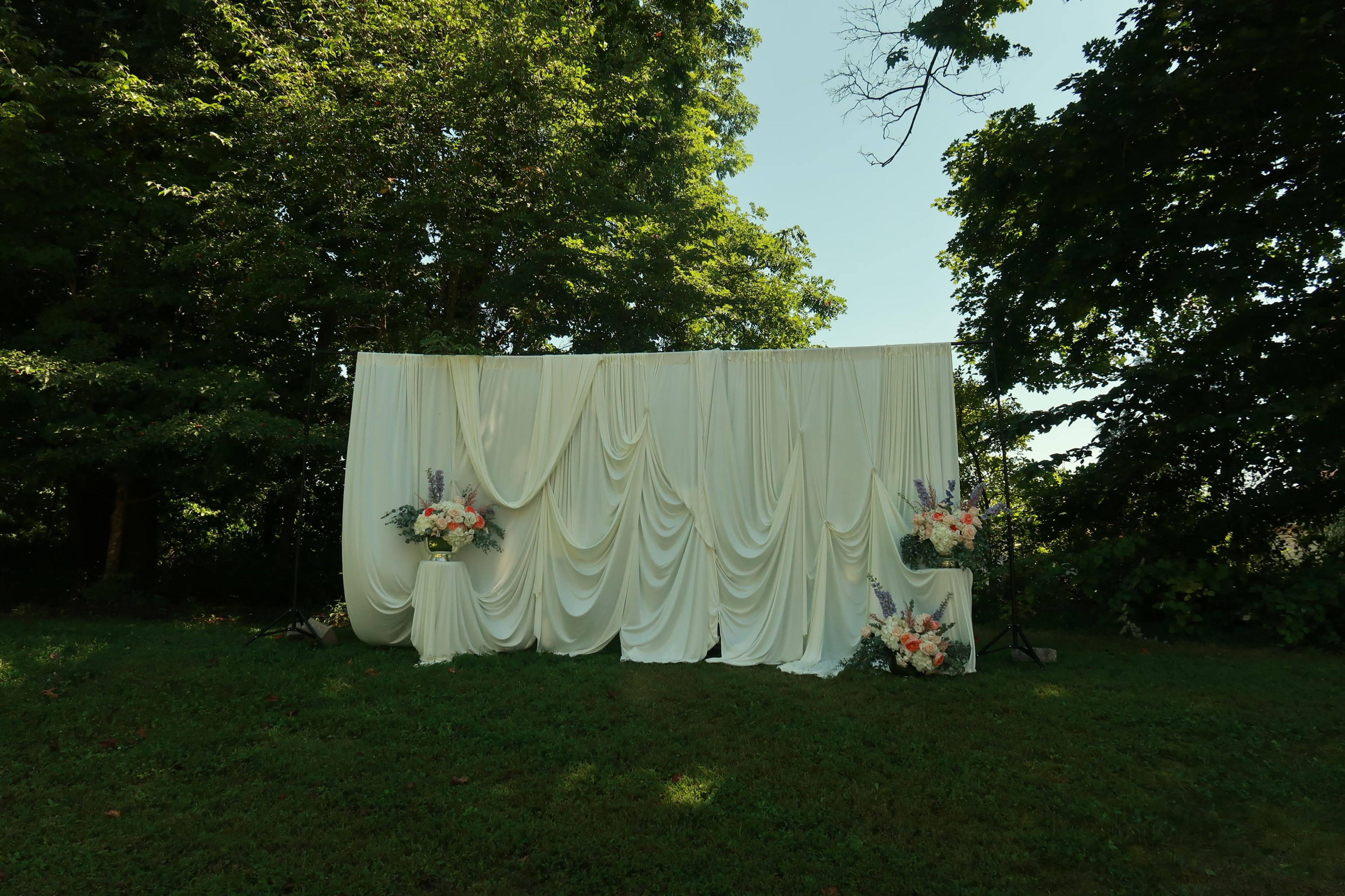 A draped welcome table set up on the lawn beneath trees