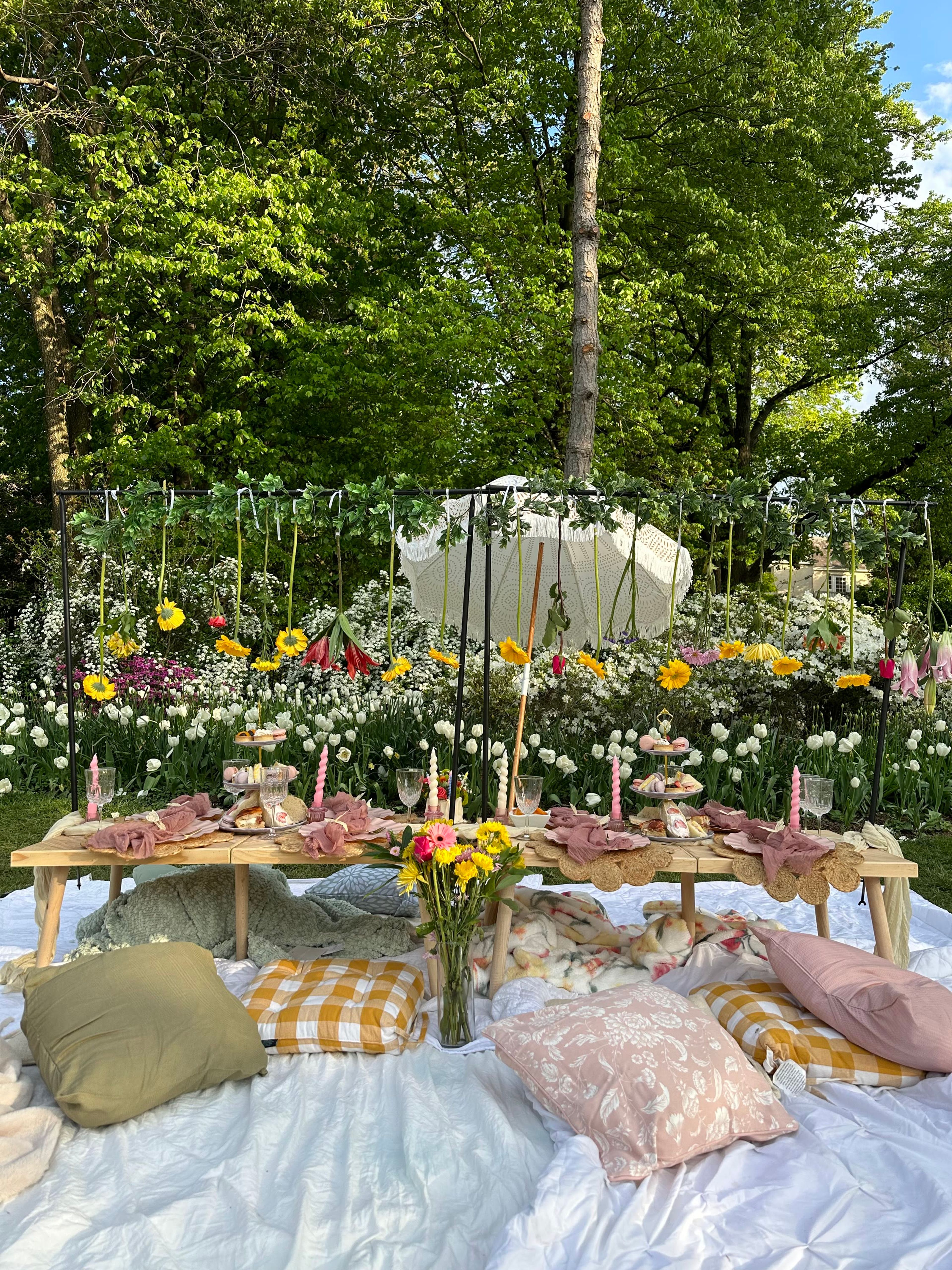 An outdoor picnic setup with a grazing table and flowers